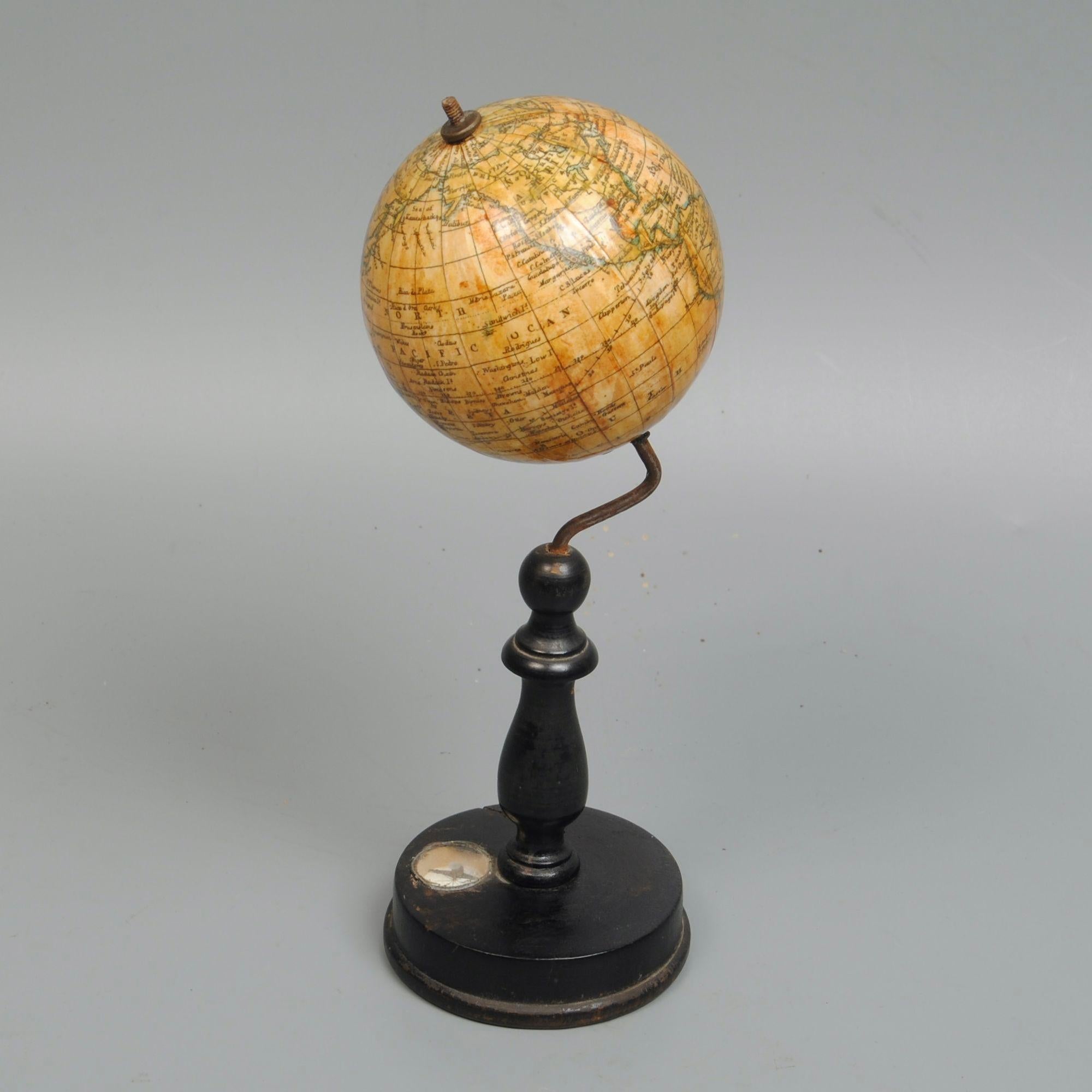 Un mappamondo in miniatura tedesco della fine del XIX secolo su un supporto ebanizzato con una bussola incastonata nella base.