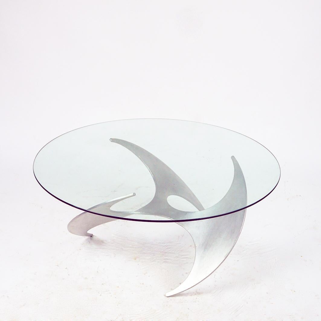 This circular eye catching Mid-Century Modern glass and Aluminum base coffee table was designed by Knut Hesterberg in the 60s and produced by Ronald Schmitt Germany in the 1960s. 
It features a sculptural aluminum propeller shaped base with a glass