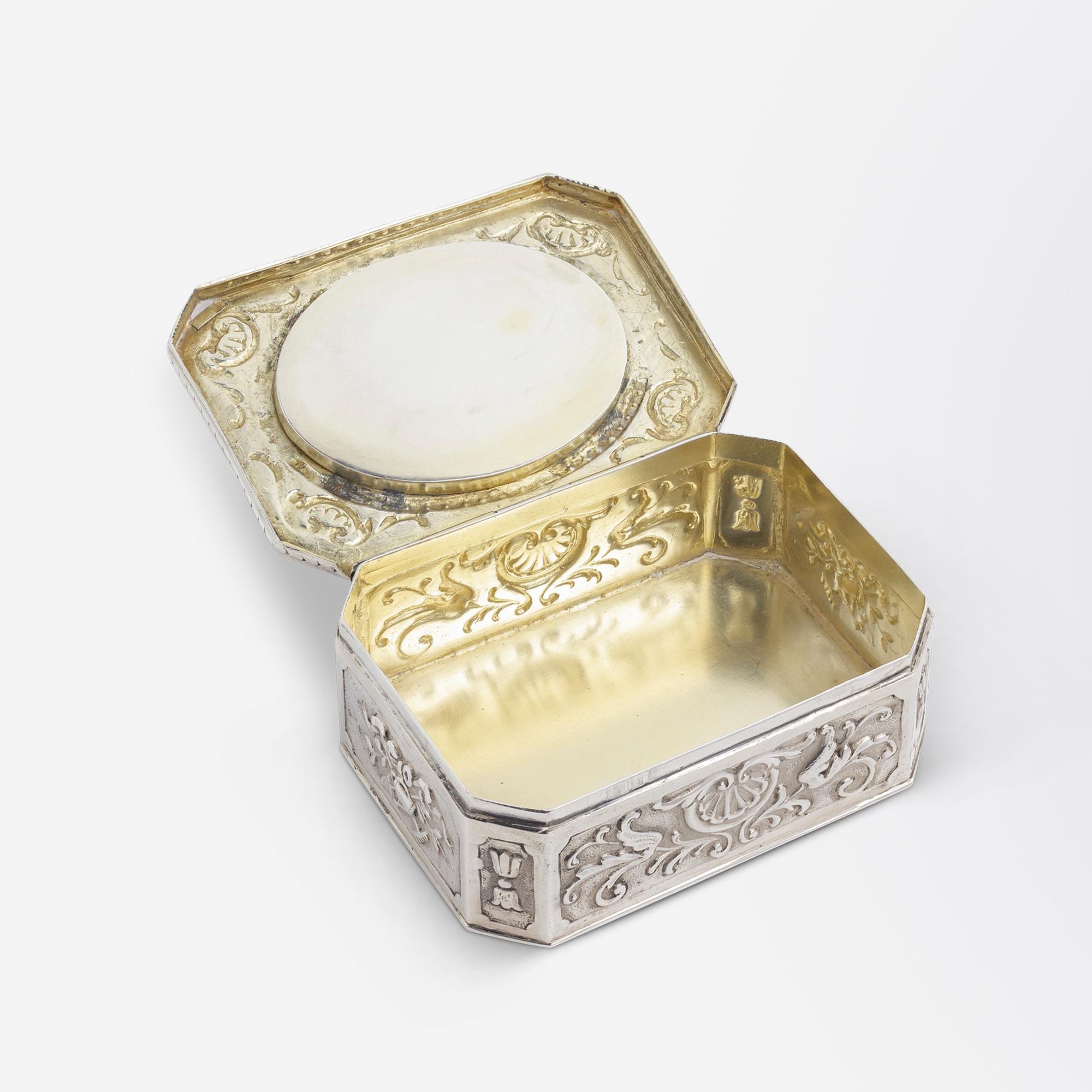 Cette charmante boîte, qui date du début du siècle, a été fabriquée en argent pur 800 et décorée d'émaux. Cette pièce, de forme octogonale, provient d'Allemagne et a été réalisée avec des détails de repoussage ornés. Au centre de la partie