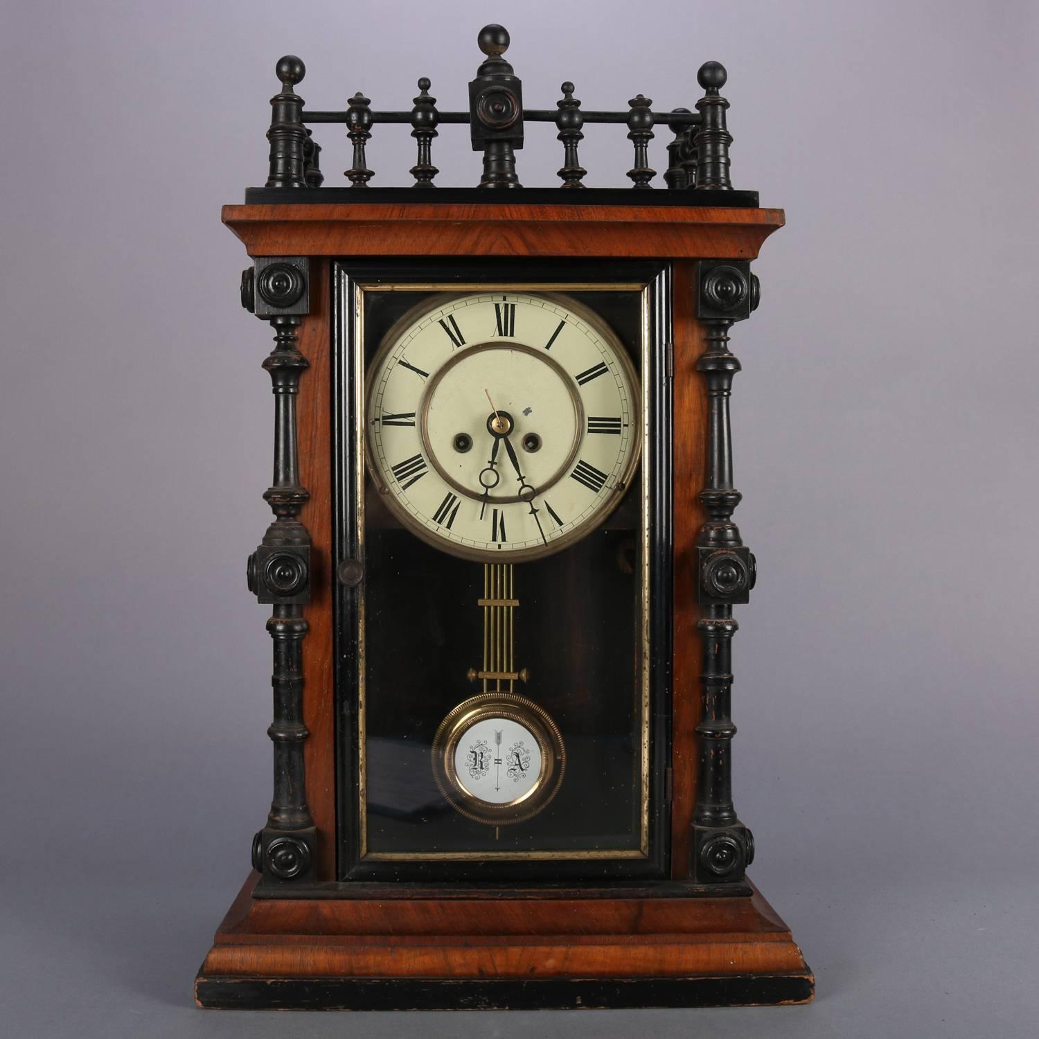 German Aesthetic Movement carved walnut clock features ebonized gallery and flanking corner columns, door frame with ebonized and gilt border, enameled face with Roman numerals, works are numbered but unmarked, elements of Black Forrest, clock works