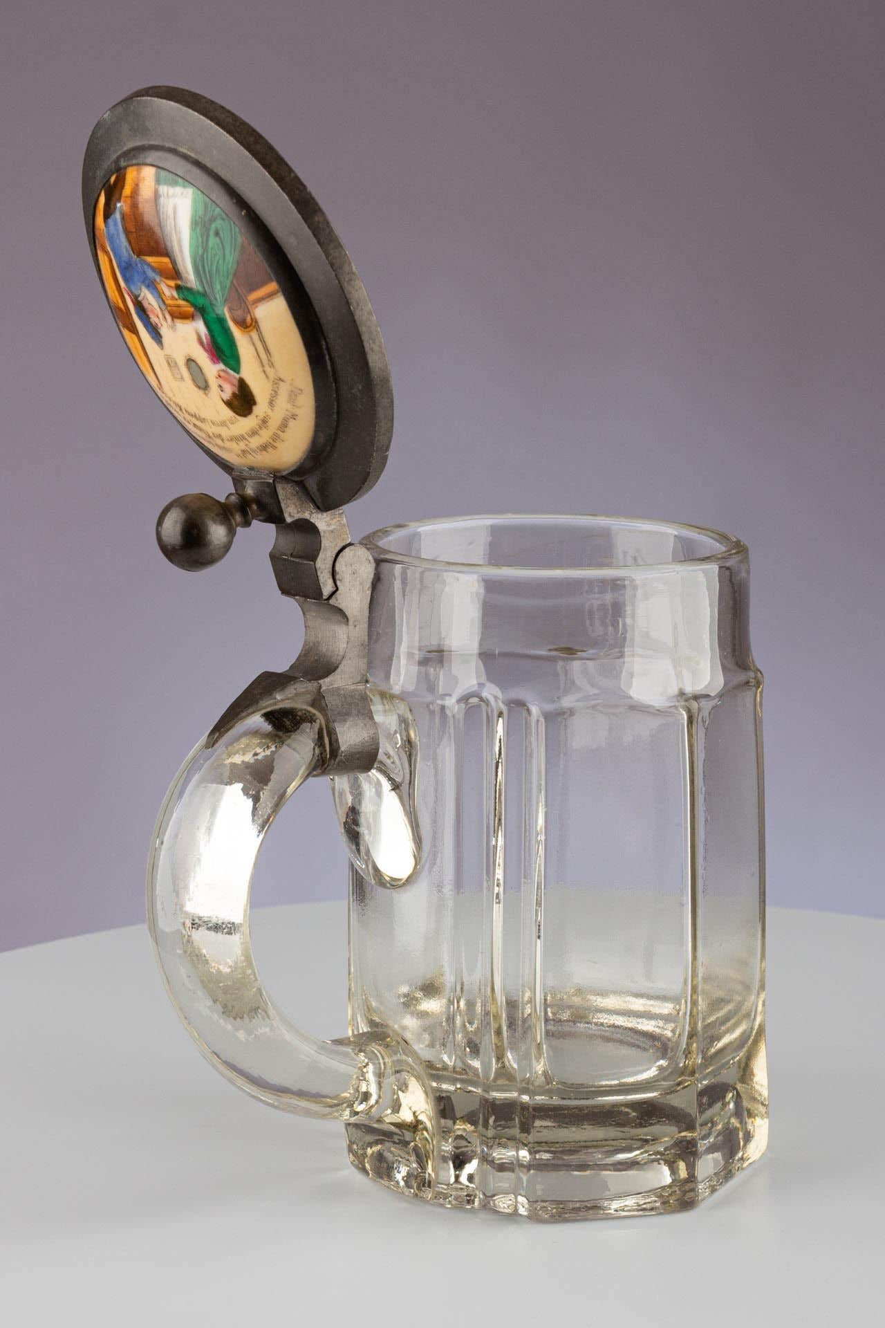 Pichet de bière en verre à couvercle, porcelaine, étain.

Allemand
Verre, étain, porcelaine 
Fin du 19e siècle 

Dimensions : H x D x L : 17cm x 14.5cm 

Fabriquée à la fin du 19e siècle, cette stèle à bière allemande incarne la longue tradition du