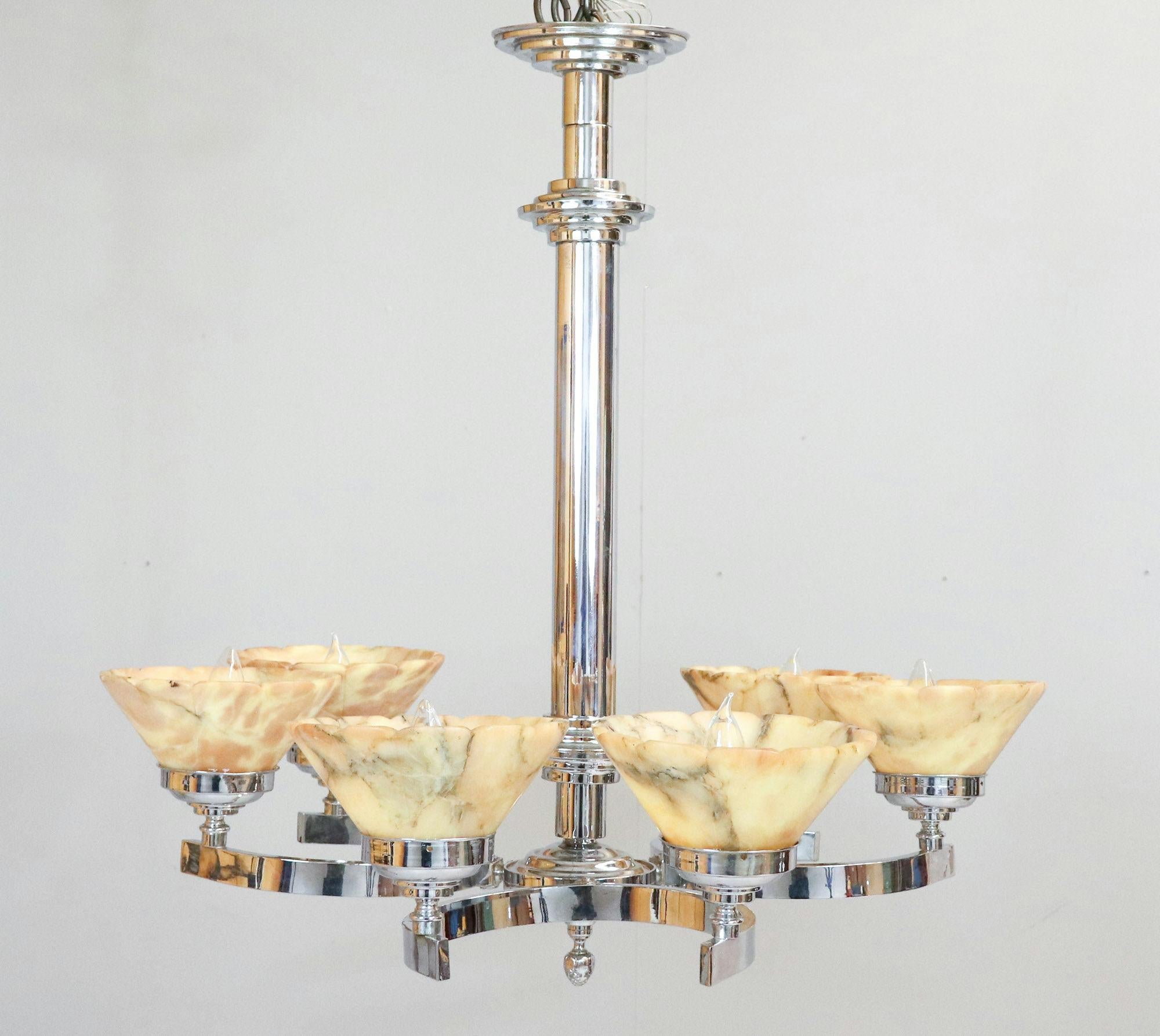 Questo lampadario in cromo Art Deco tedesco del 1940 è dotato di paralumi in alabastro in un caldo mix marmorizzato di toni gialli e beige, con venature. I paralumi conici a tromba in alabastro hanno dei bei bordi smerlati che si fondono con le