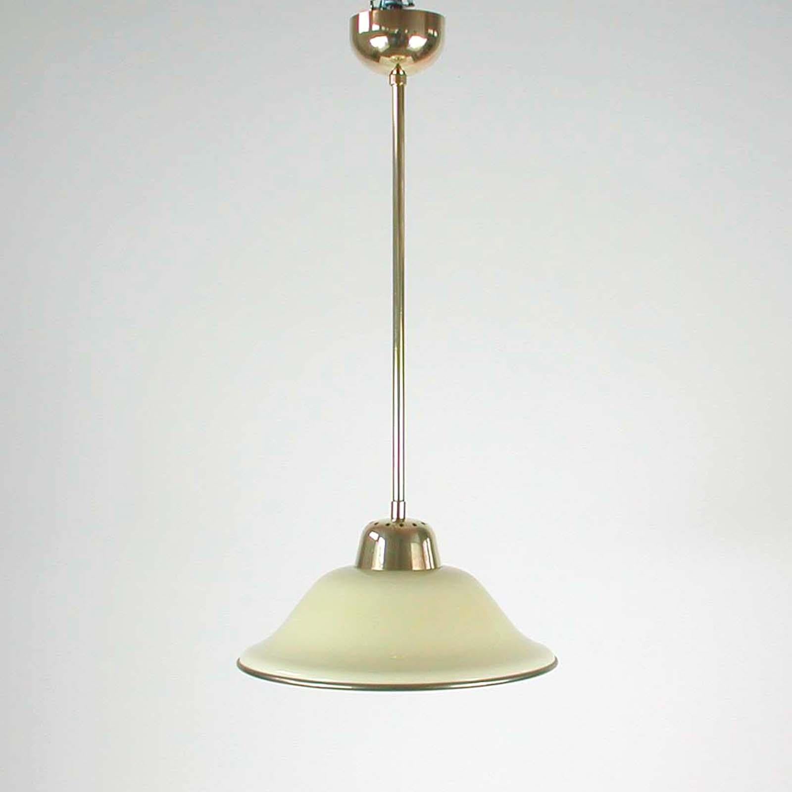 Cet élégant pendentif allemand a été conçu et fabriqué en Allemagne dans les années 1930. La lampe est en laiton et possède un abat-jour en verre opalin de couleur crème au design Bauhaus typique avec un bord en laiton. Bon état vintage avec une