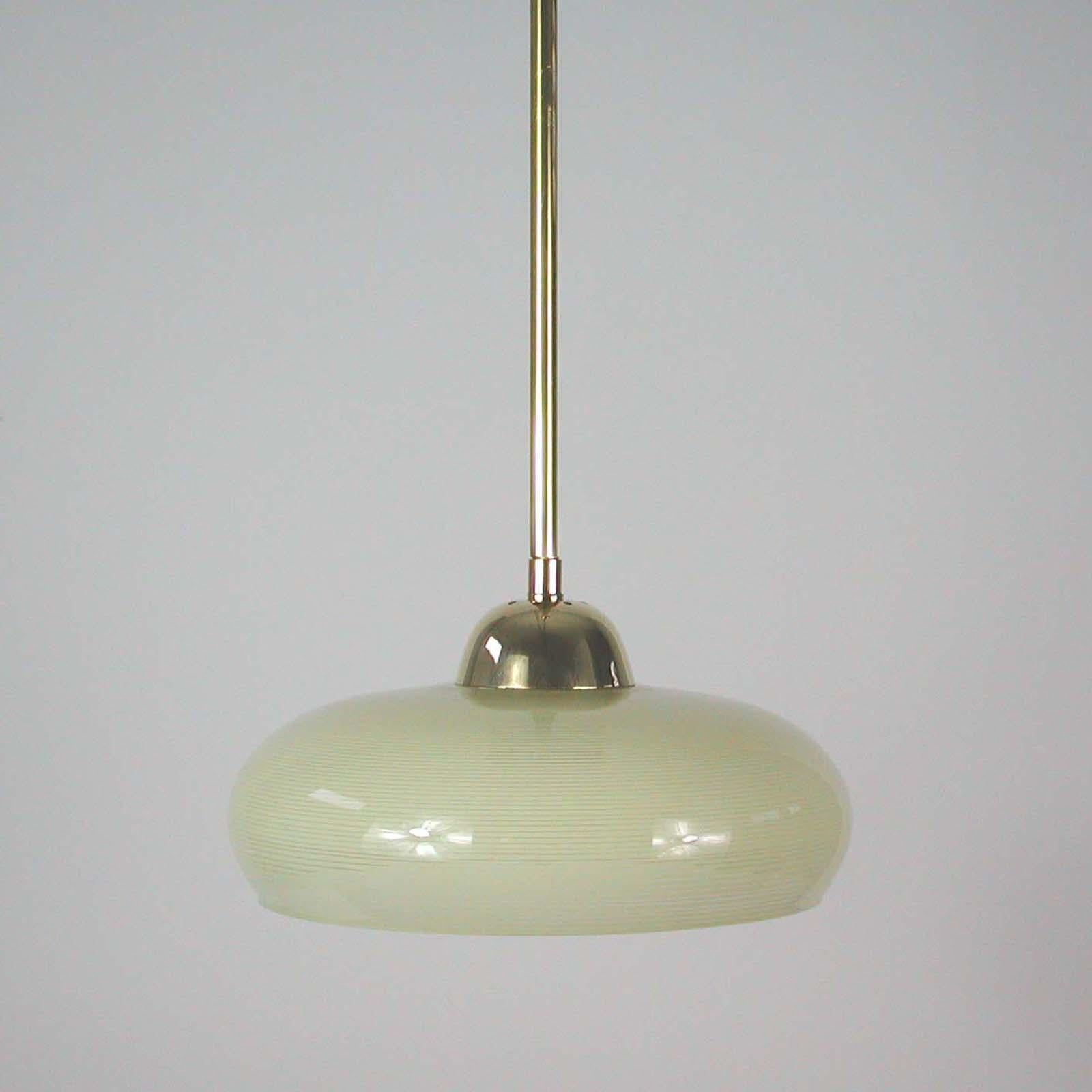 This elegant German pendant was designed and manufactured in Germany in the 1930s. The light is made of brass and has got a cream colored opaline glass shade in typical Bauhaus Design with striped glass decor. Good vintage condition with one E27
