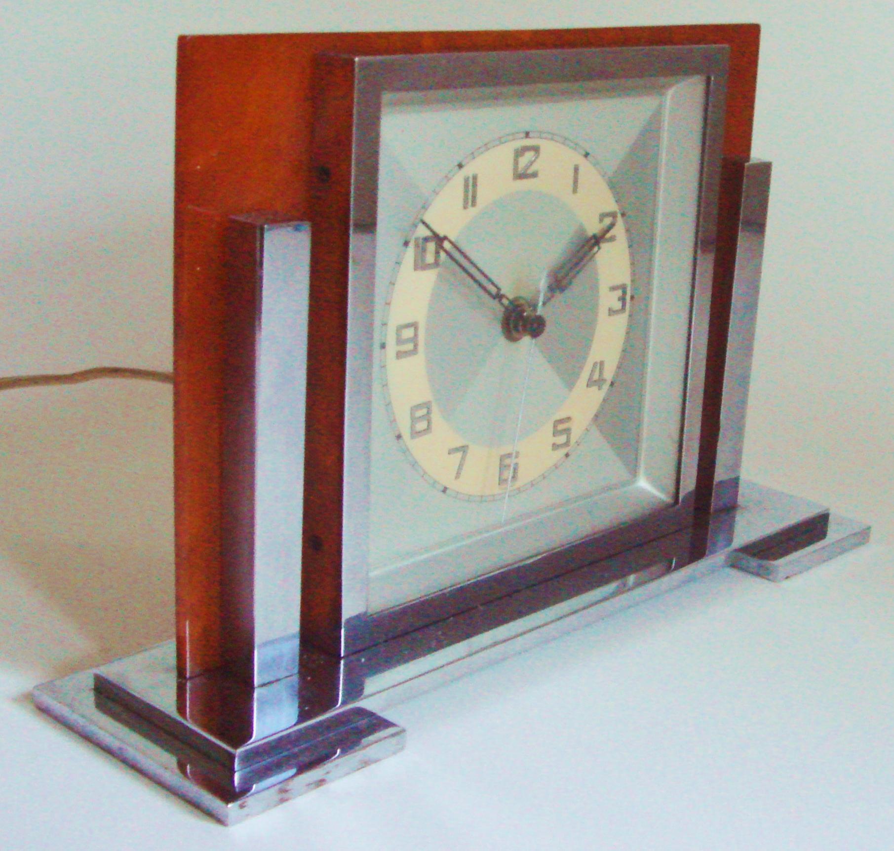 This strongly designed German Art Deco electric desk clock is brilliant in its simplicity. It features a stepped chrome base, chrome bezel and two chrome pillars flanking this bezel. The clock motor housing is totally chrome plated and it is