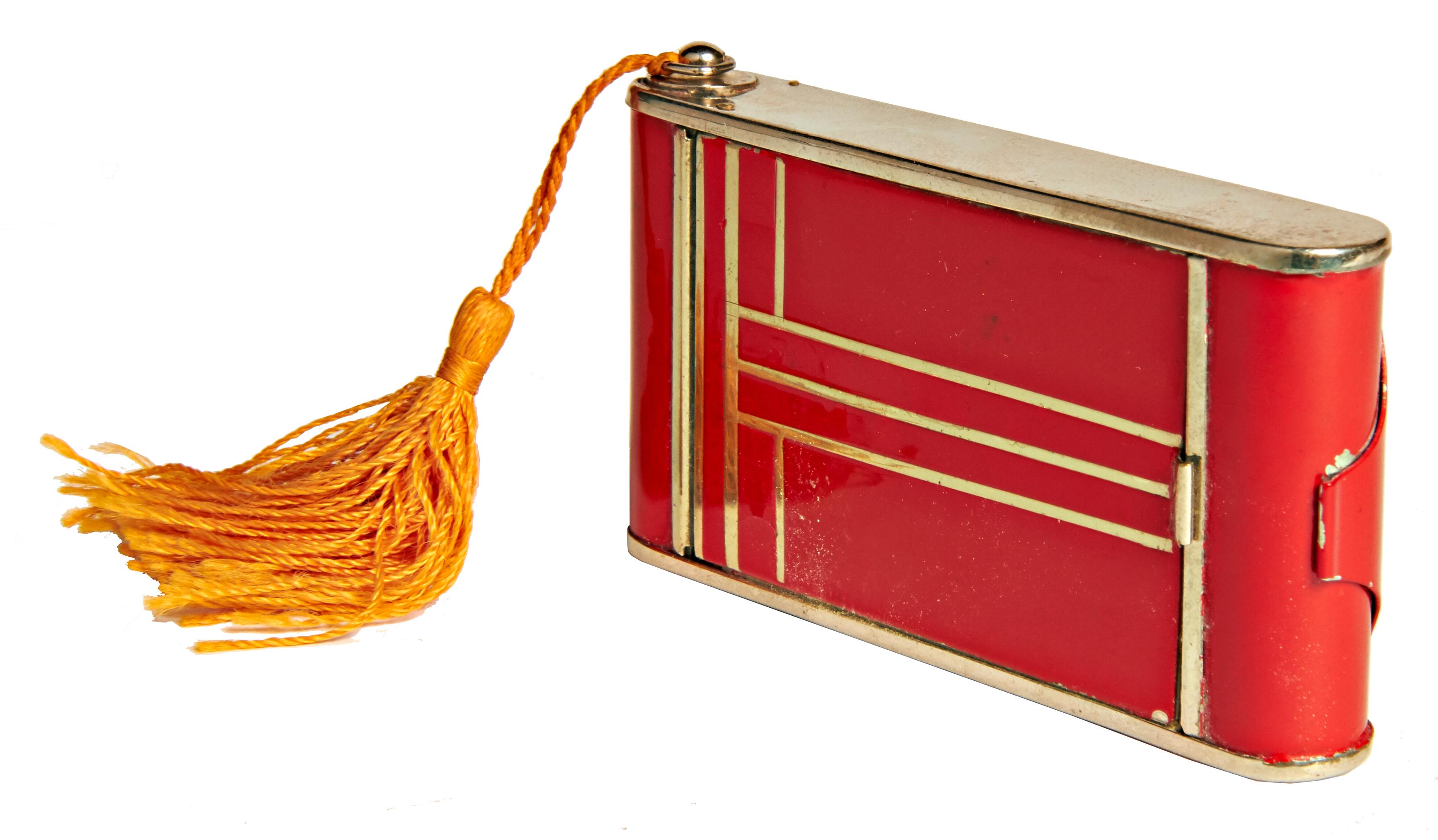 This beautifully designed German Art Deco camera compact/minaudiere features red enamel accented with a geometric design of chrome lines on the front with a solid red back. On one side it has a large lift-top compact with mirror and complete with