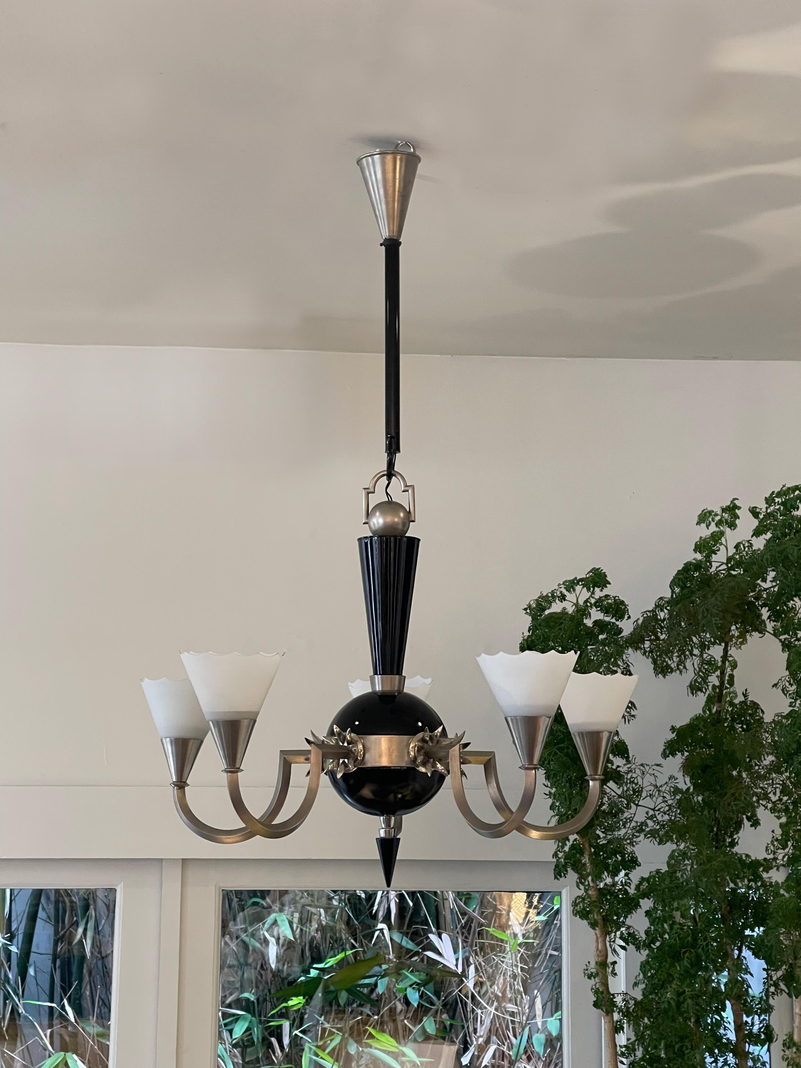 Five-arm chrome chandelier with stylized floral leaves jutting out by arms. Center ball, spike and stem are all black lacquer. Five delicate milk glass shades with a scallop trim.