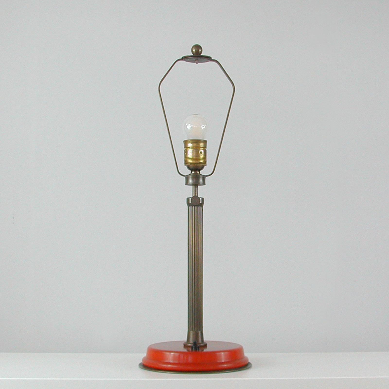 Diese ungewöhnliche Art-Déco-Tischlampe wurde in den 1920er bis 1930er Jahren in Deutschland entworfen und hergestellt. Er verfügt über einen höhenverstellbaren Korpus aus bronziertem Messing auf einem rot/rubin/karminroten Bakelit-Sockel. Sehr
