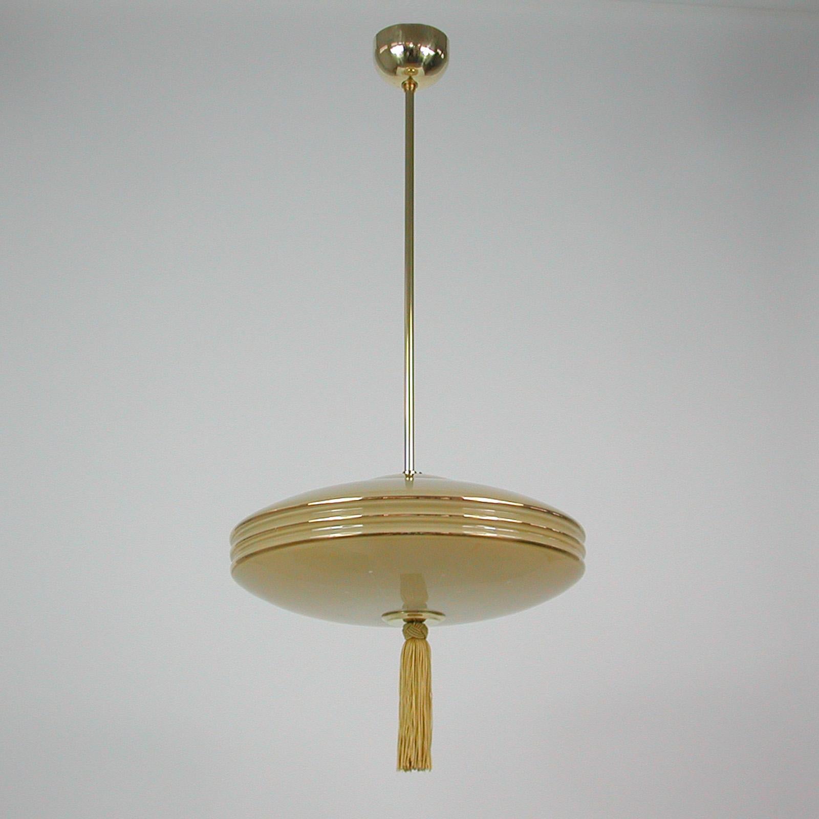 This unusual fixture was designed and manufactured in Germany in the 1930s during the Bauhaus period.
It features an ivory colored glass lampshade, a bronze silk tassel and brass hardware.

The light has been rewired and requires one E27 bulb.