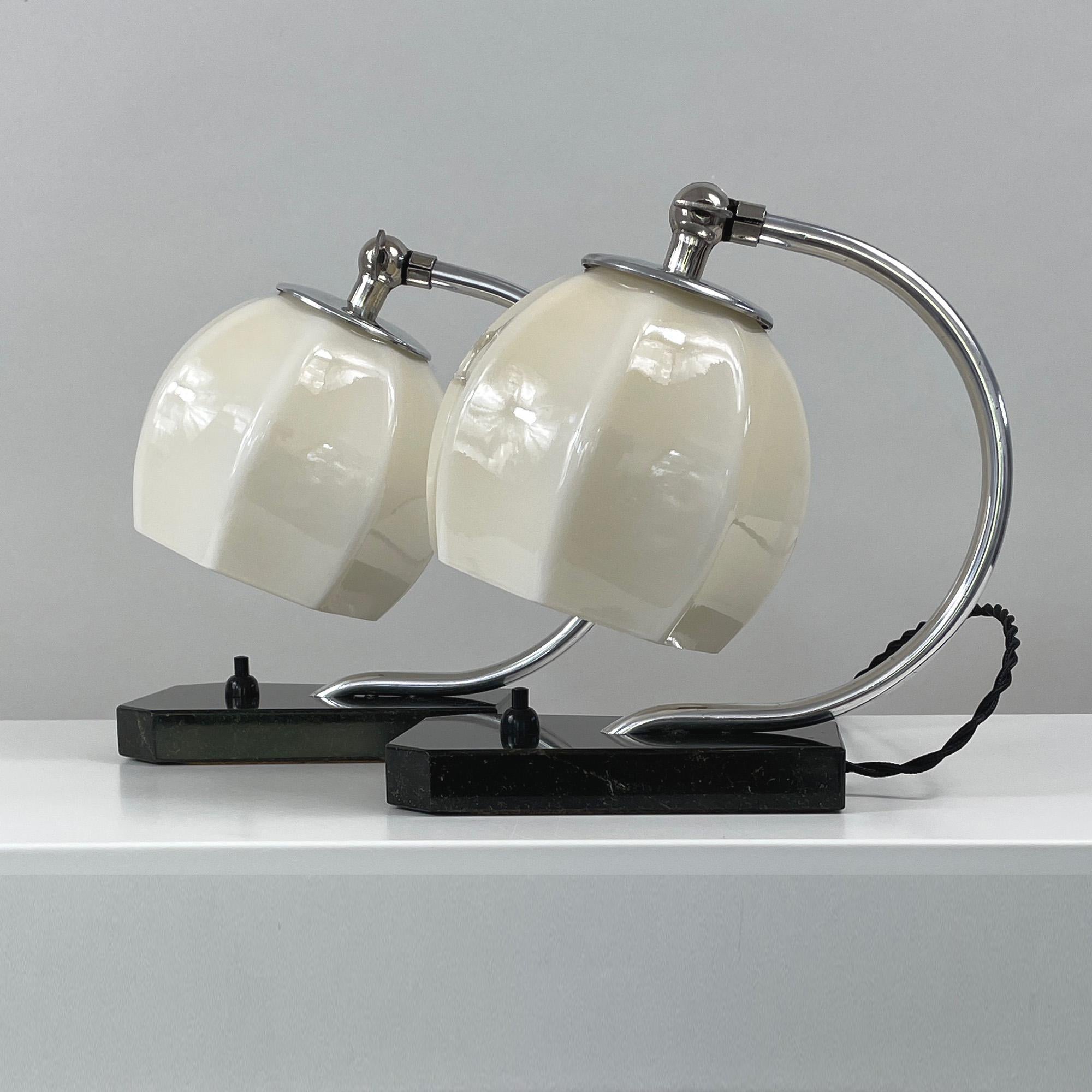 These unusual table or bedside lamps were designed and manufactured in Germany in the 1930s during the Art Deco / Bauhaus period. They feature black marble bases, aluminum lamp arms and cream colored opaline lampshades. The lamps shades are