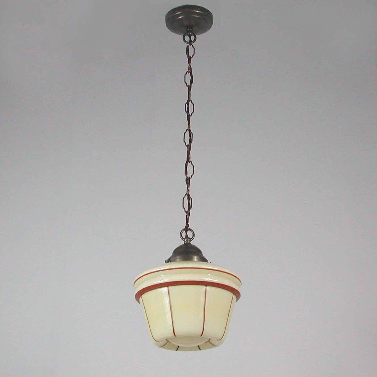 This beautiful Art Deco lantern was designed and manufactured in Germany in the 1920s-1930s. It features a cream colored Opaline lamp shade and patinated brass shade holder, chain and canopy. The lamp shade has got a light brown / dark red enameled