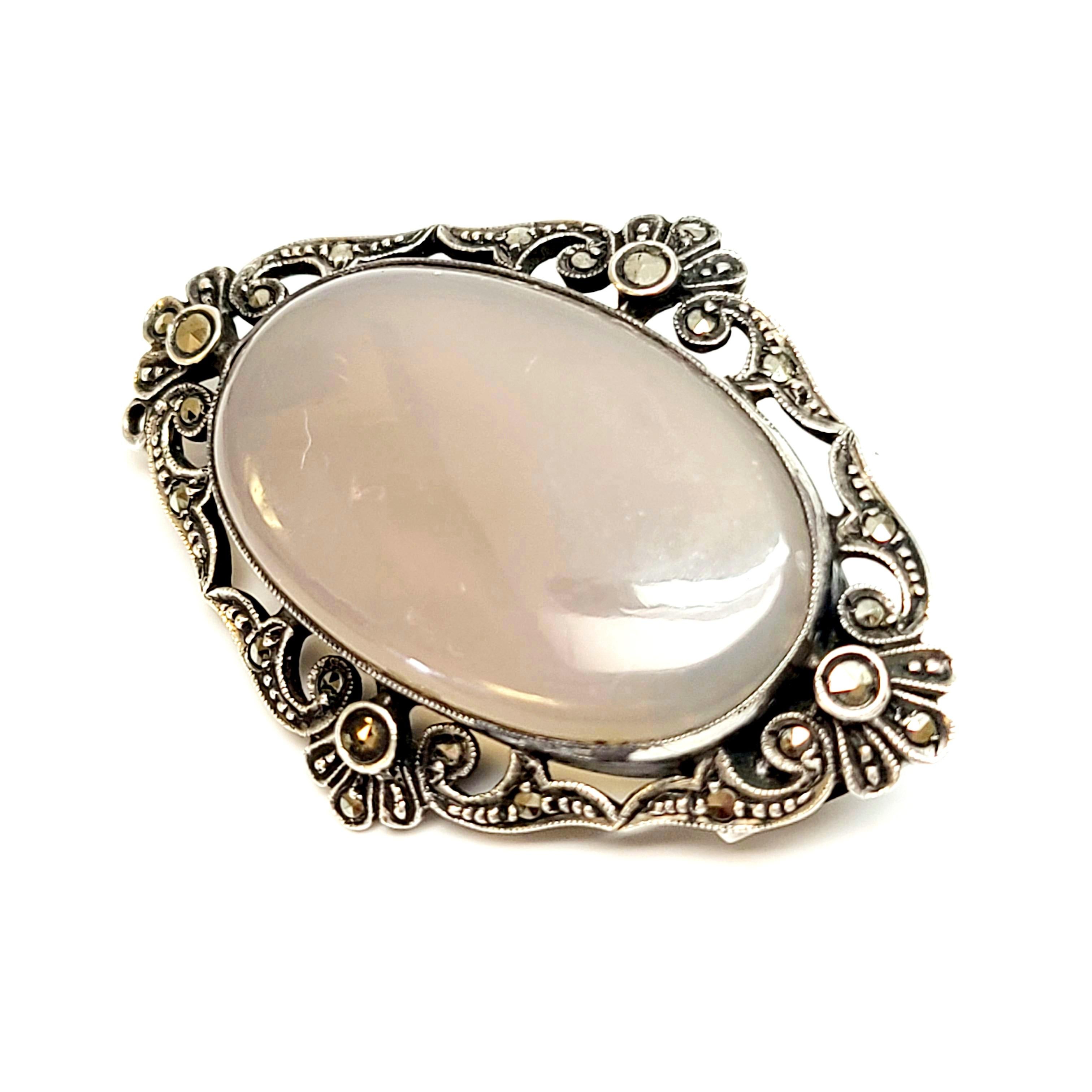 A German sterling silver, marcasite and gray stone pin/brooch.

An oval translucent gray stone is bezel set in an ornate sterling silver and marcasite setting.

Measures approx 1 3/4