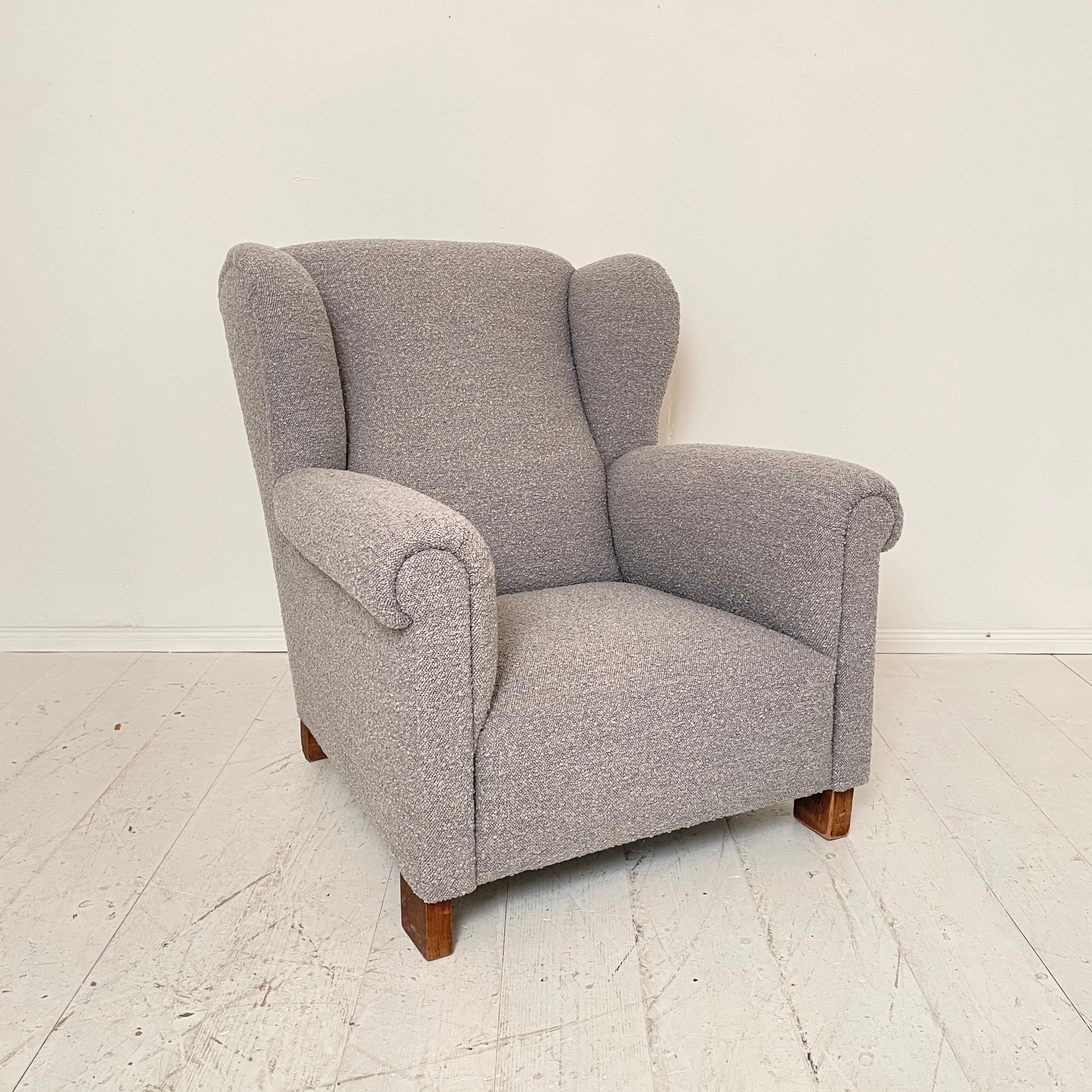 This great wingback chair from the 1920s has been completely reupholstered and covered with a high quality gray boucle fabric. 
The armchair is very comfortable and a great highlight for your home.
A unique piece which is a great eye-catcher for