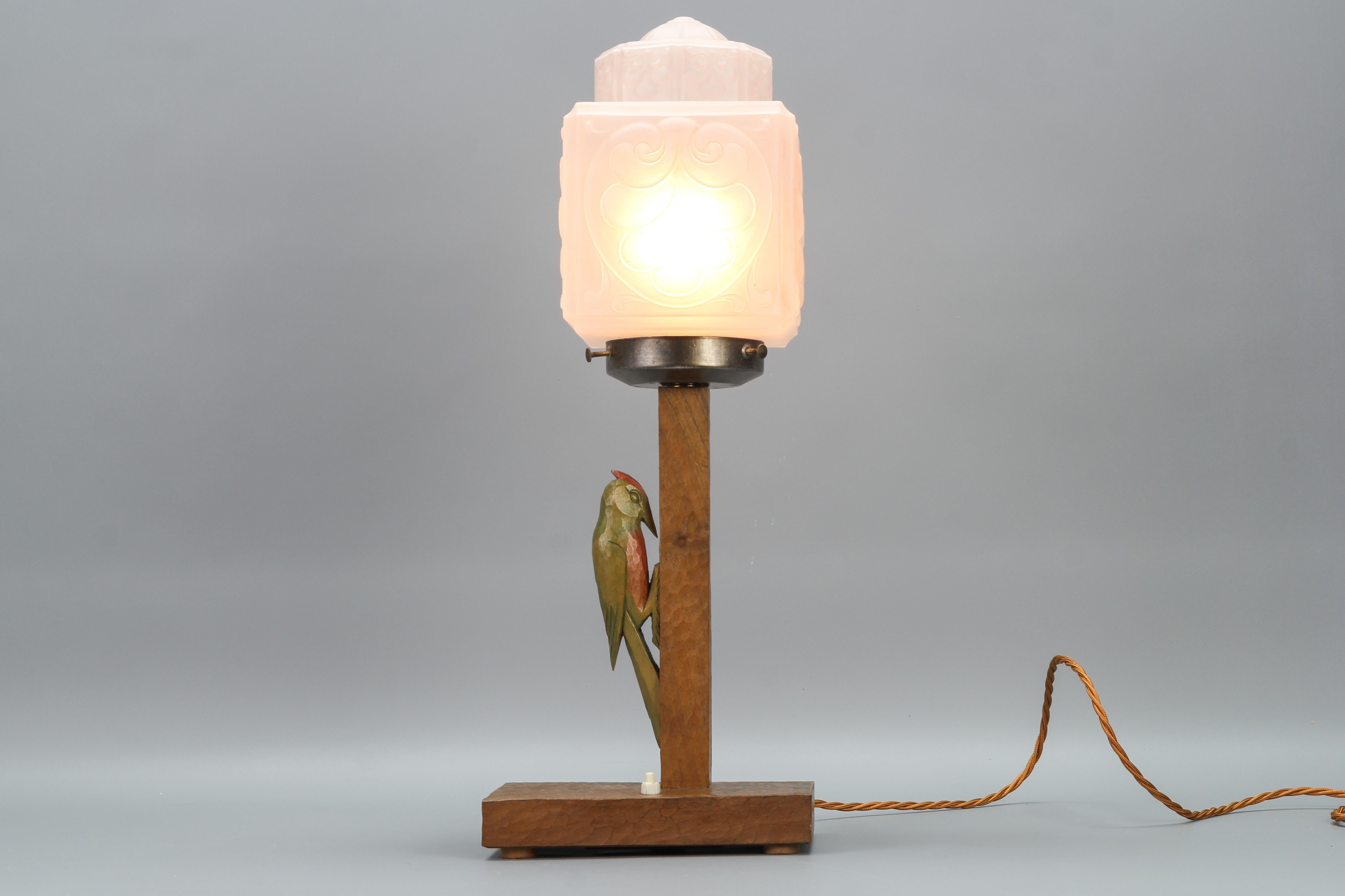German Art Deco wooden and frosted glass table lamp with a Woodpecker from the 1930s.
This large and beautiful Art Deco period table lamp features an ornate white frosted glass lampshade and hand-carved walnut base with an adorable woodpecker figure
