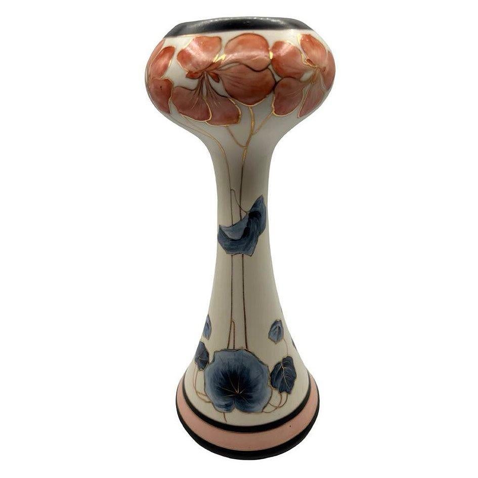 This is a beautiful piece of German Art Nouveau from 1910 by Royal Dux. The style of this vase is a high waist with painted lily pads at the bottom and lily flowers outlined with golden accents. The bottom contains the serial number 