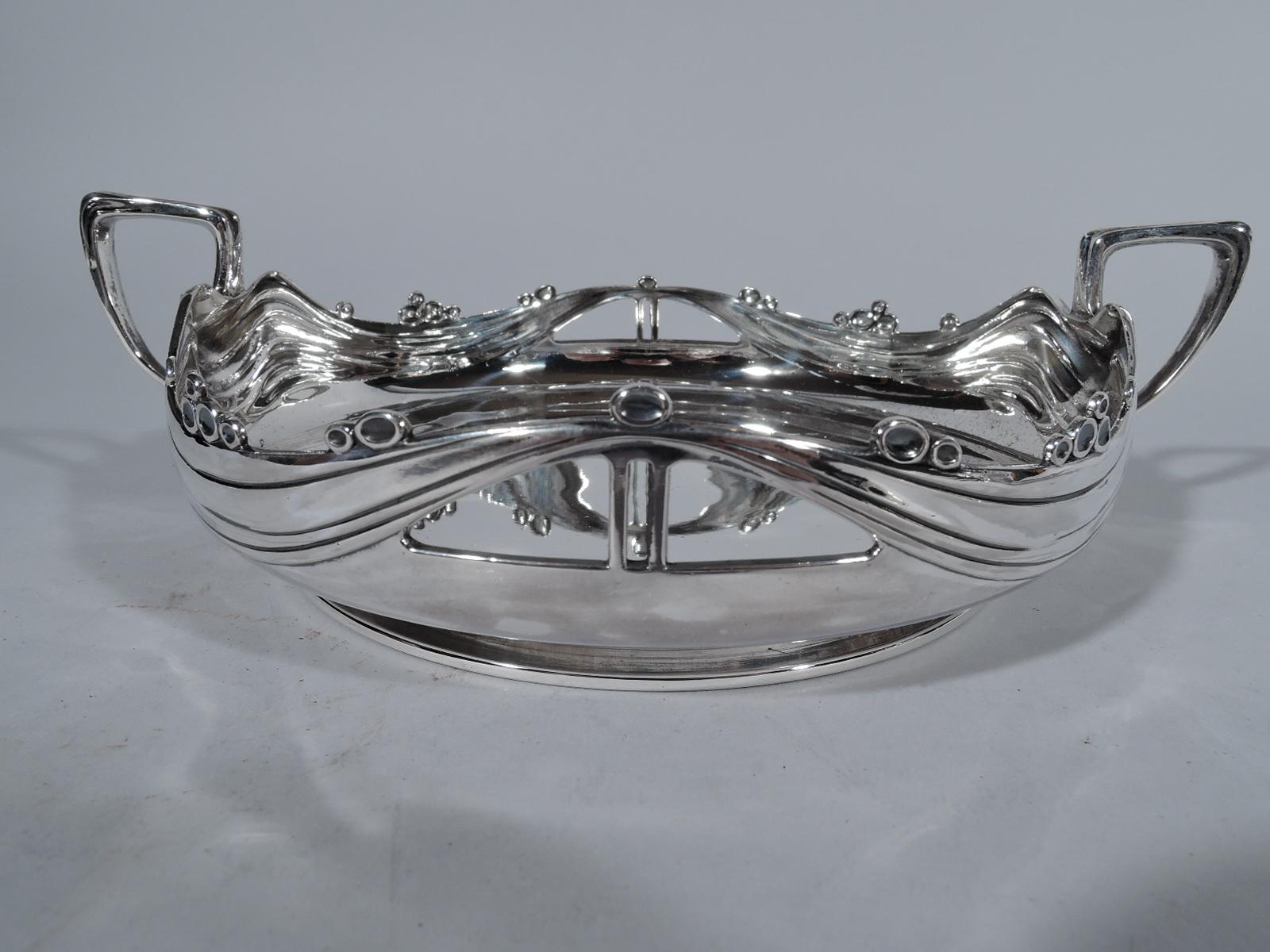 German Jugendstil sterling silver bowl. Round with wavy sides and open lunettes propped up tent-style with double poles. Sides have tooled wavy lines and dot clusters are applied to rim. Scroll-bracket side handles. Short foot. Hallmarked. Heavy
