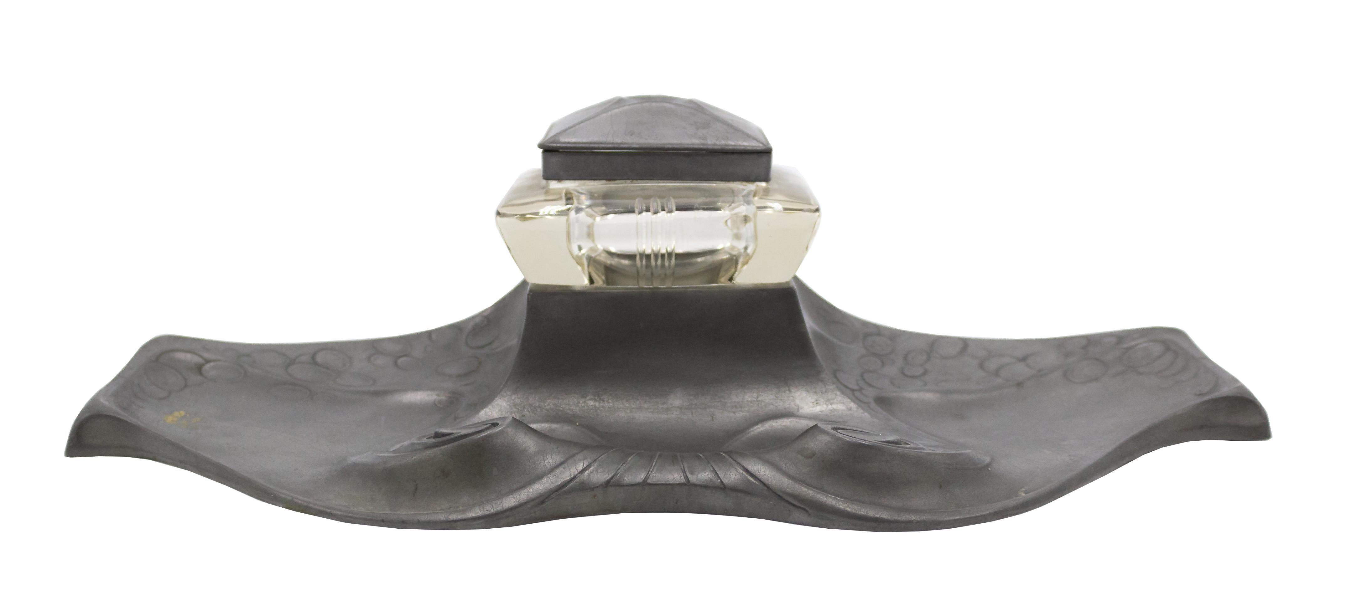 German Art Nouveau pewter inkstand with scroll designs supporting a square cut glass inkwell with a square molded pewter lid.
 