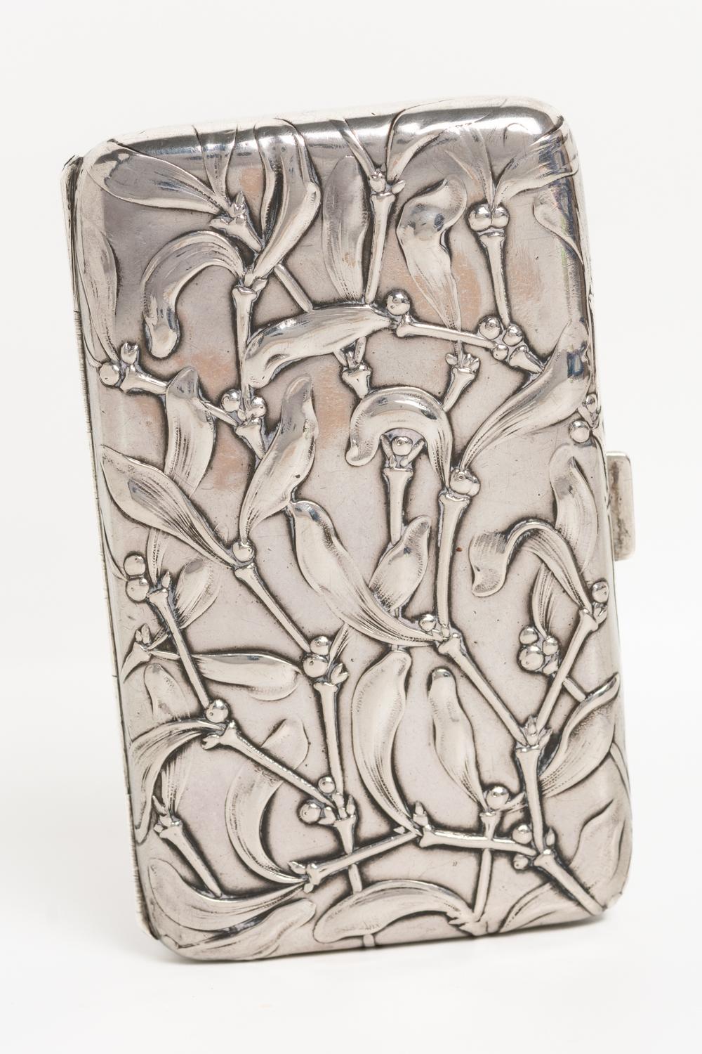 This beautiful and finely crafted German solid silver cigarette case is made circa 1890 and features a beautiful repousse mistletoe design in a very detailed Art Nouveau style. The large rectangular case opens to reveal silver gilt interior and