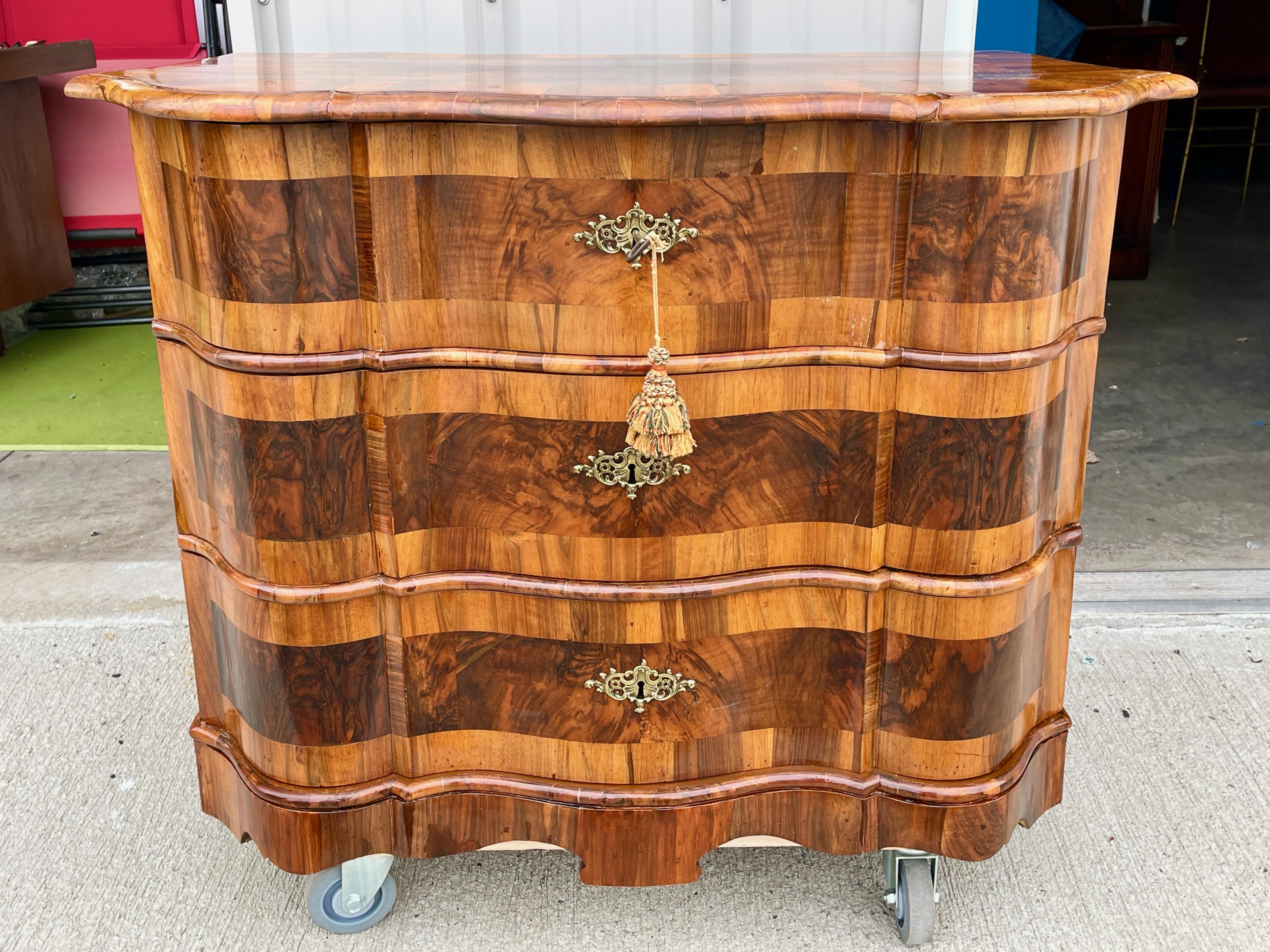 Cassettone barocco tedesco a tre cassetti, metà del XVIII secolo, impiallacciato in noce e pannelli intarsiati, finitura semilucida, fronte a serpentina. Raccordi in ottone. Serrature e chiavi funzionanti. Splendidamente restaurato.