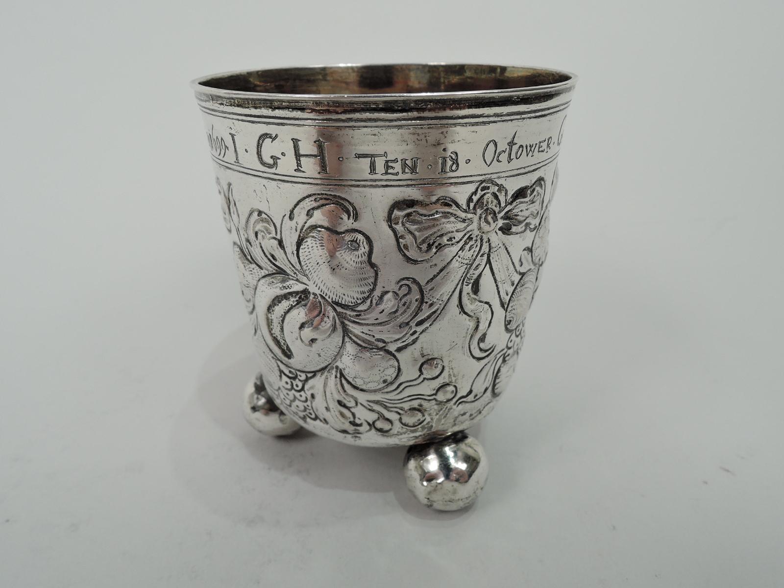German Baroque Classical silver wine beaker, 17th century. Urn bowl with three splayed ball supports. Clusters of fruits and vegetables and pendant ribbon bows. At top engraved presentation on occasion of child born in 1699. Gilt-washed interior.