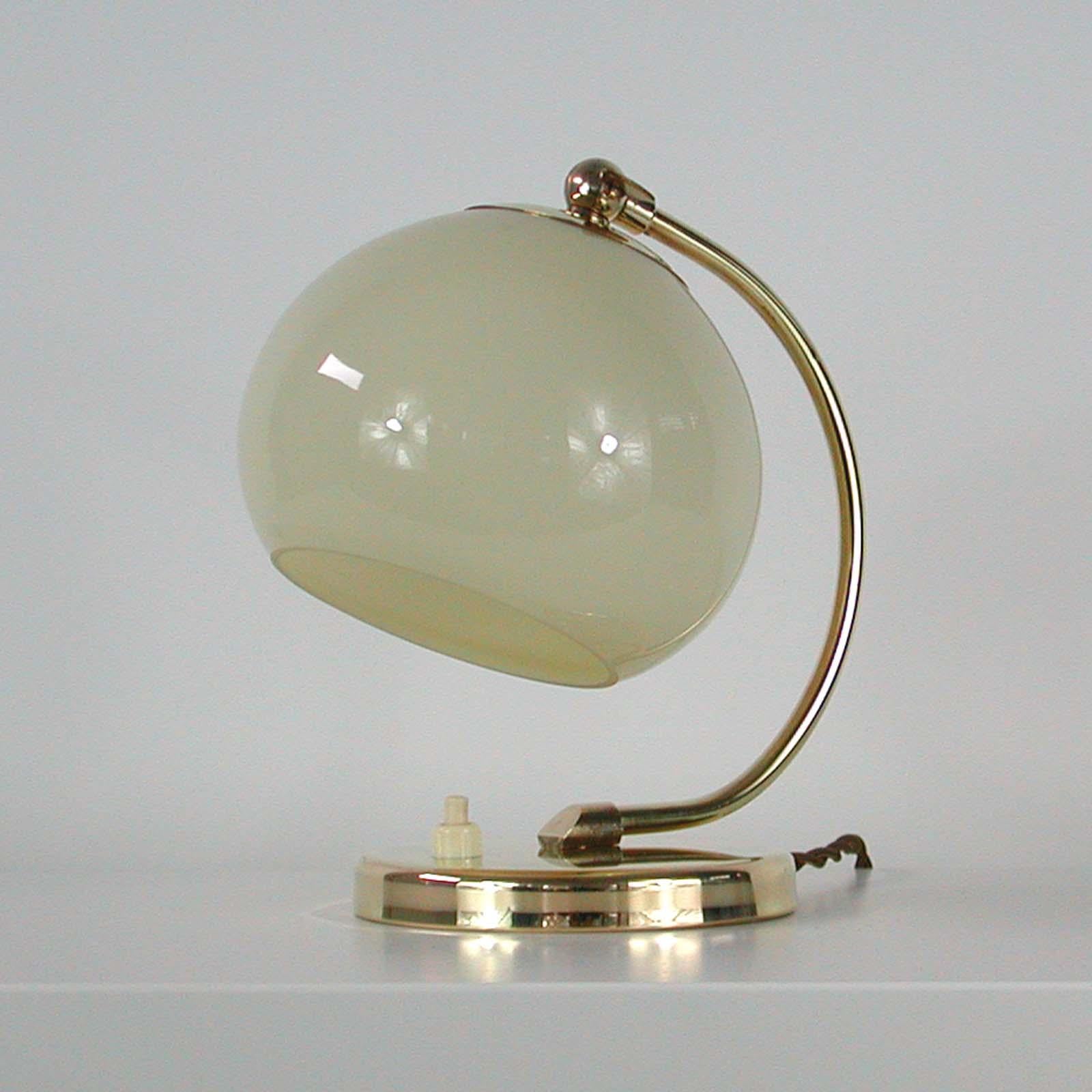 This pretty vintage table or bedside lamp was made in Germany in the 1930s during the Bauhaus period. It is made of brass and has got an adjustable lamp shade made of opaline glass.

Rewired with new silk cord and ready for use in any country of
