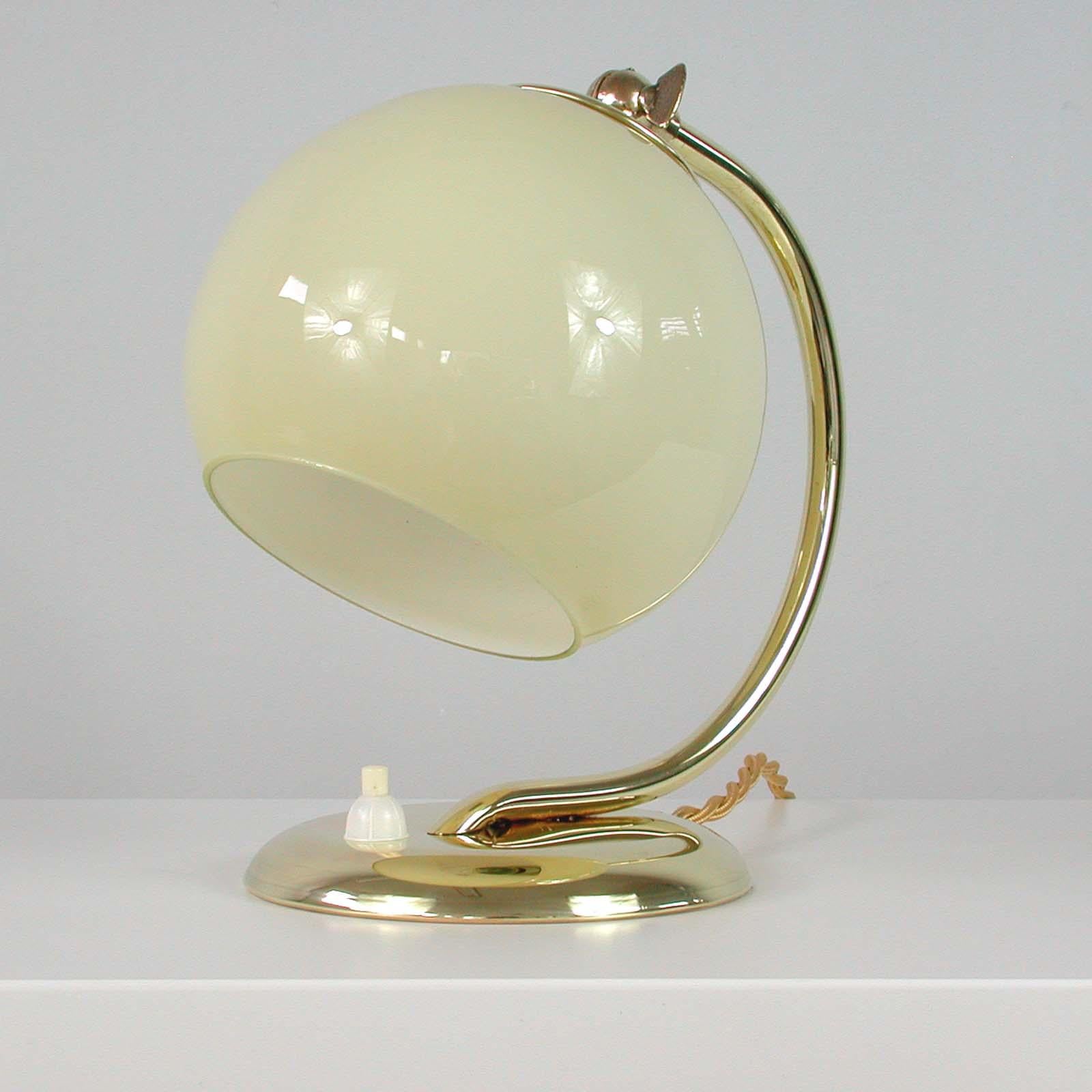 This unusual vintage table or bedside lamp was made in Germany in the 1930s during the Bauhaus period. It is made of polished brass and has got an adjustable lamp shade in cream/yellow opaline glass.

The lamp can be used as a table lamp as well
