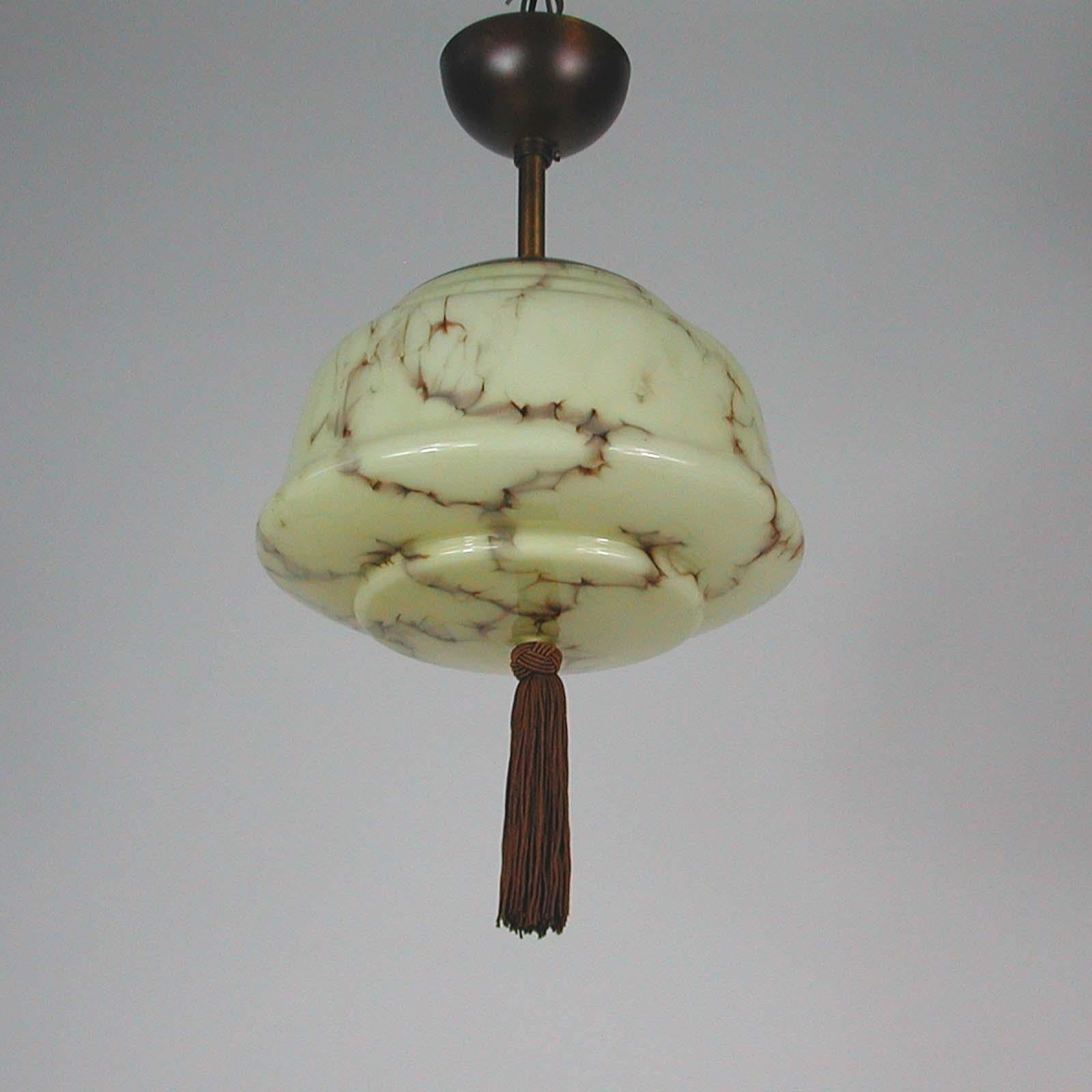 This elegant German pendant or flushmount was designed and manufactured in Germany in the 1920s-1930s. The light is made of patinated brass and has got a cream colored opaline marbled glass shade in typical Bauhaus Design. Good vintage condition