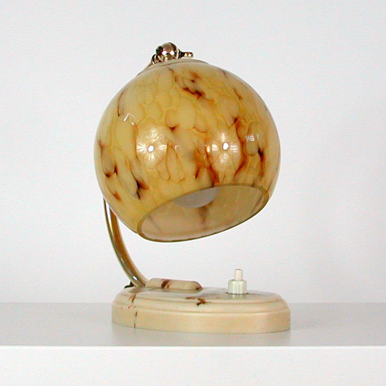 This unusual vintage table or bedside lamp was made in Germany in the 1930s-1940s during the Bauhaus period. It is made of polished brass and has got an adjustable lamp shade in cream marbled opaline glass. The base is made of plastic, possibly