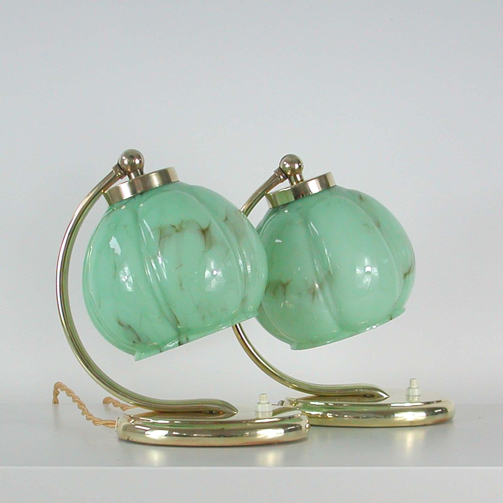 These table or bedside lamps were designed and manufactured in Germany in the 1930s during the Bauhaus period. They are made of brass and have got pale green marbled opaline glass lamp shades.

Both lamps have been rewired with new silk cord for