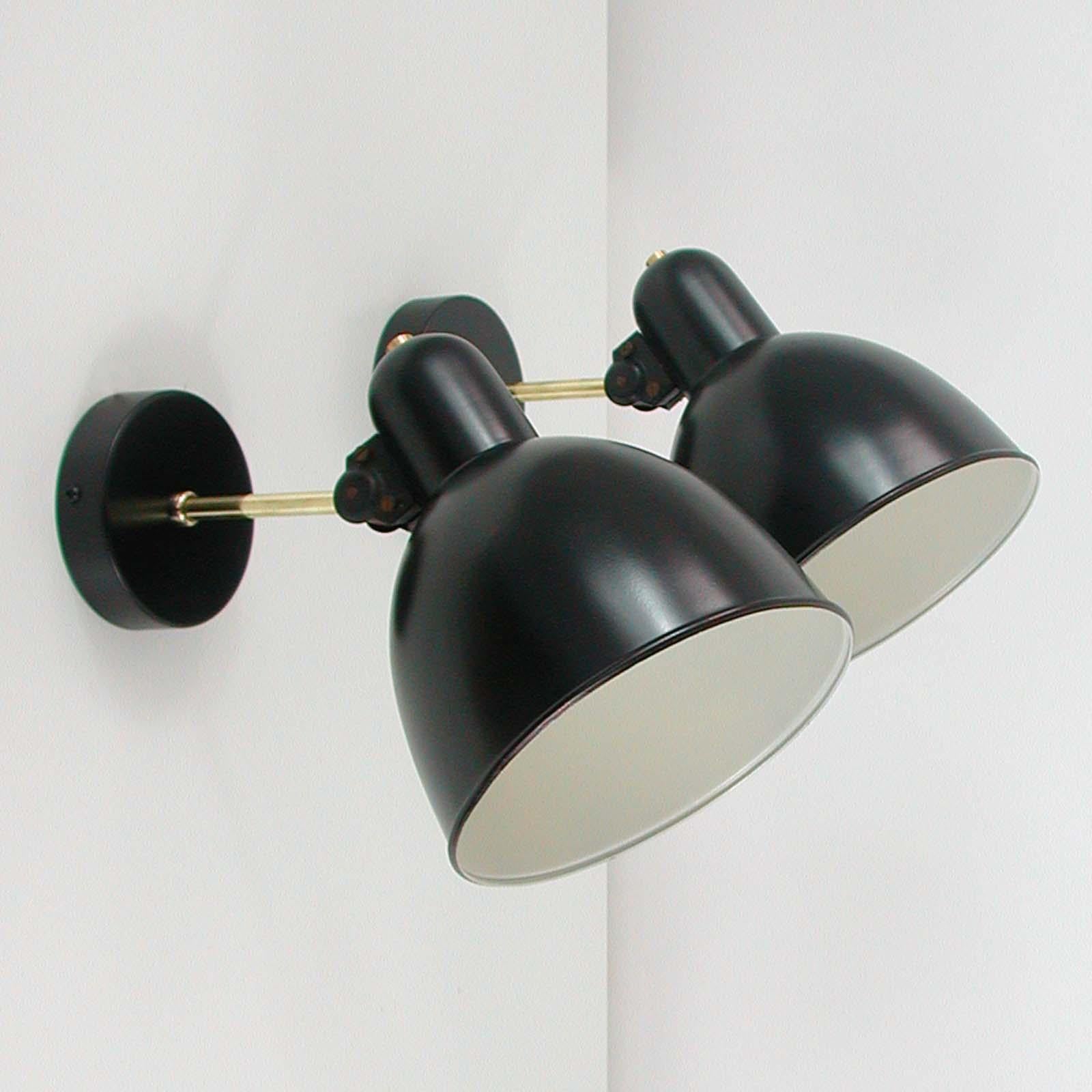 These vintage industrial sconces were manufactured in Germany in the 1930s. They feature a black lacquered metal lampshade, a black back plate and a brass lamp arm. The lamp shades are adjustable. The lamp arm is customizable. 

The design is