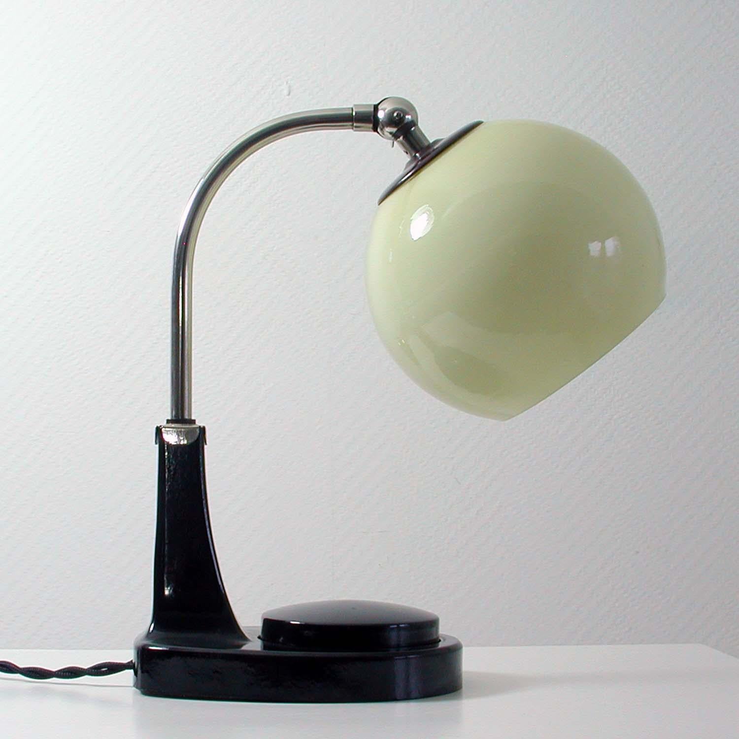 This vintage table light was designed by Marianne Brandt and manufactured in Germany in the 1930s during the Bauhaus period. It has got a bakelite base, a chrome lamp arm and an adjustable lamp shade in cream opaline glass.

The lamp that can be