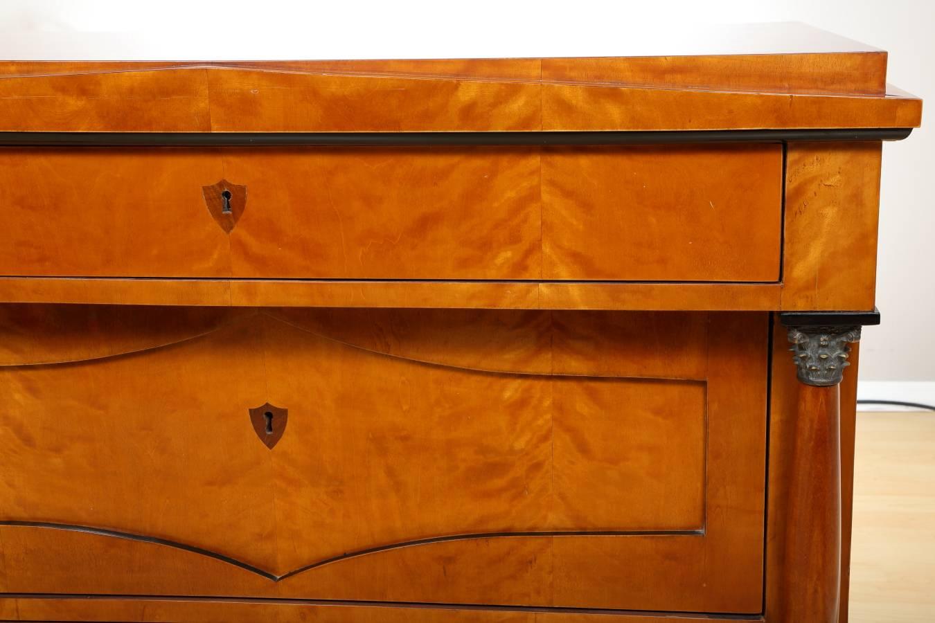 German Biedermeier birch chest of drawers, circa 1840. Elegant Biedermeier commode with decorative columns crowned with bronze capitals. Ebonized wood details at front. The piece has been restored with respect to the original wood color and patina,