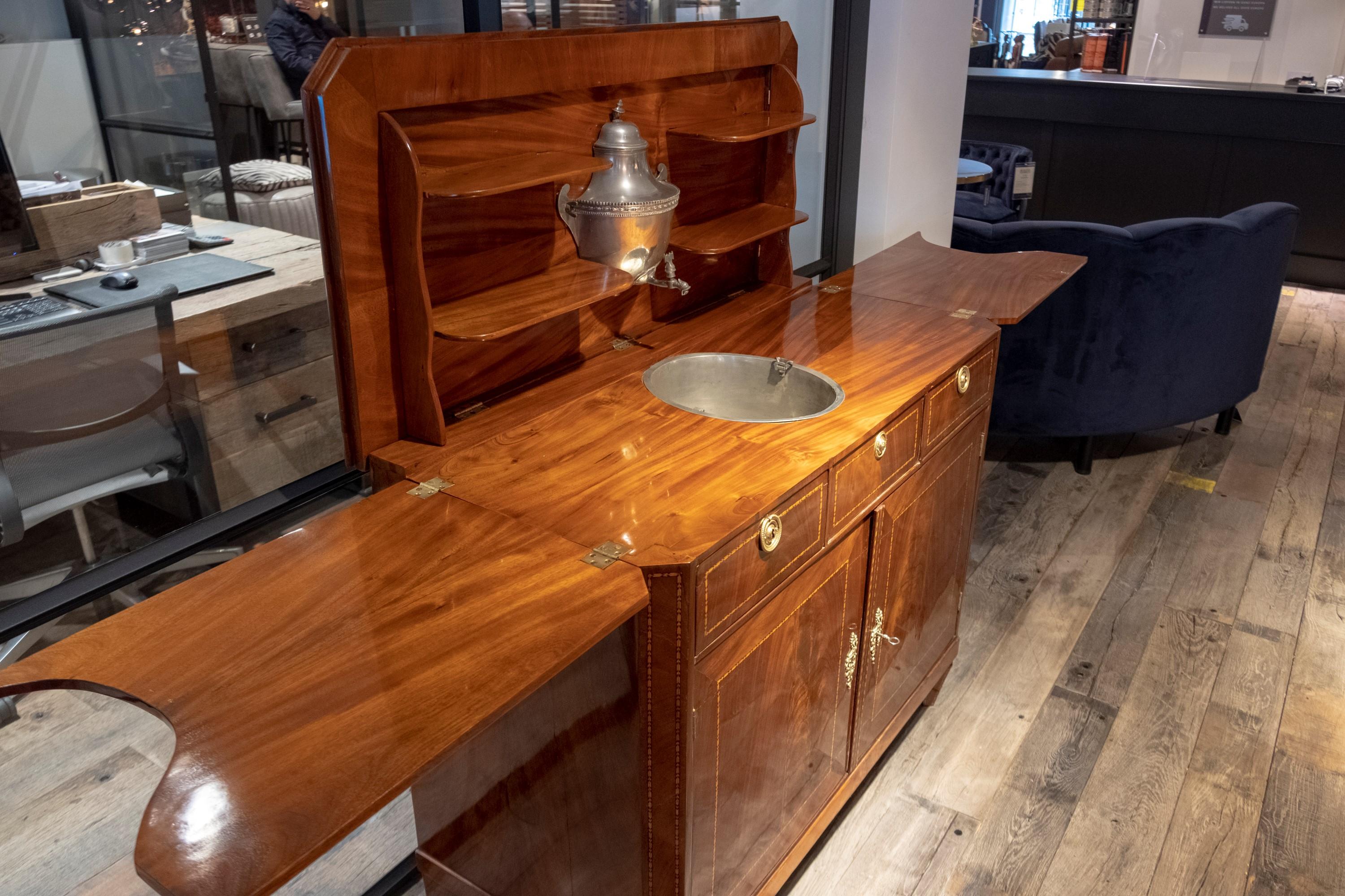 A German antique folding buffet from the Biedermeier period. The folding buffet is made of mahogany wood and the sink of tin. The reservoir is original. The folding buffet was made around the year 1830.
Width is 115cm and extended 231cm.
 