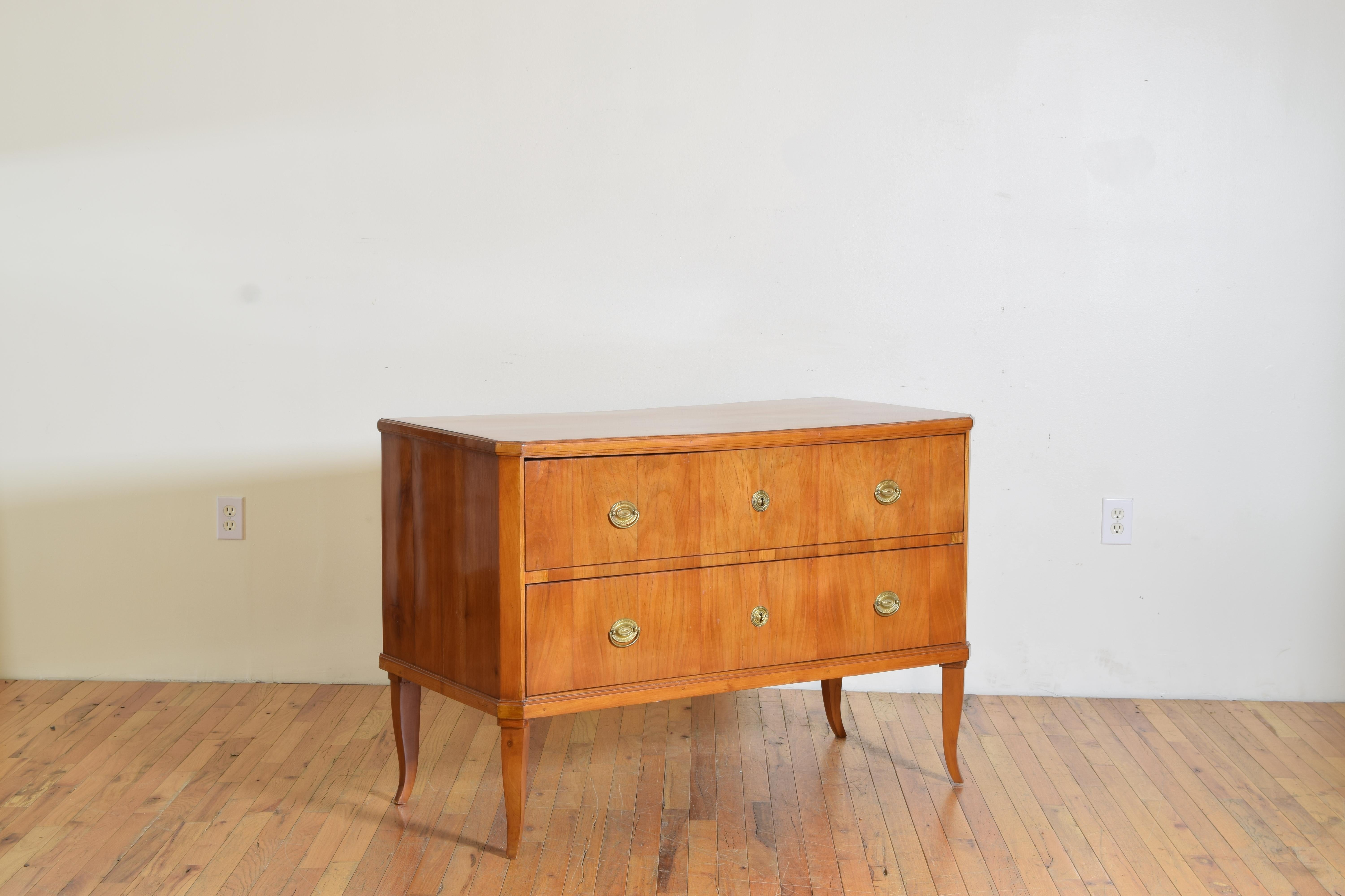 Having a rectangular top with slightly canted corners atop a conforming case housing two drawers with original brass hardware, the case raised on flared tapering legs