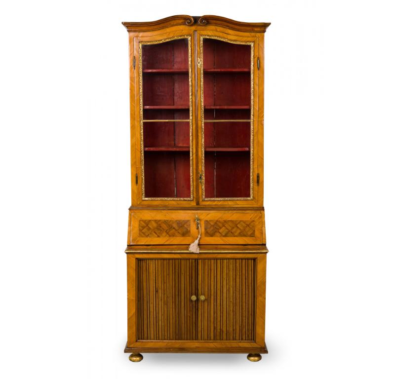 German Biedermeier (18th Century) olivewood secretary / bookcase in shaped rectangular with the top section having a hinged 2-door shelved cabinet with glass windows bordered by parcel gilt molded trim; the bottom section features a trapezoidal top