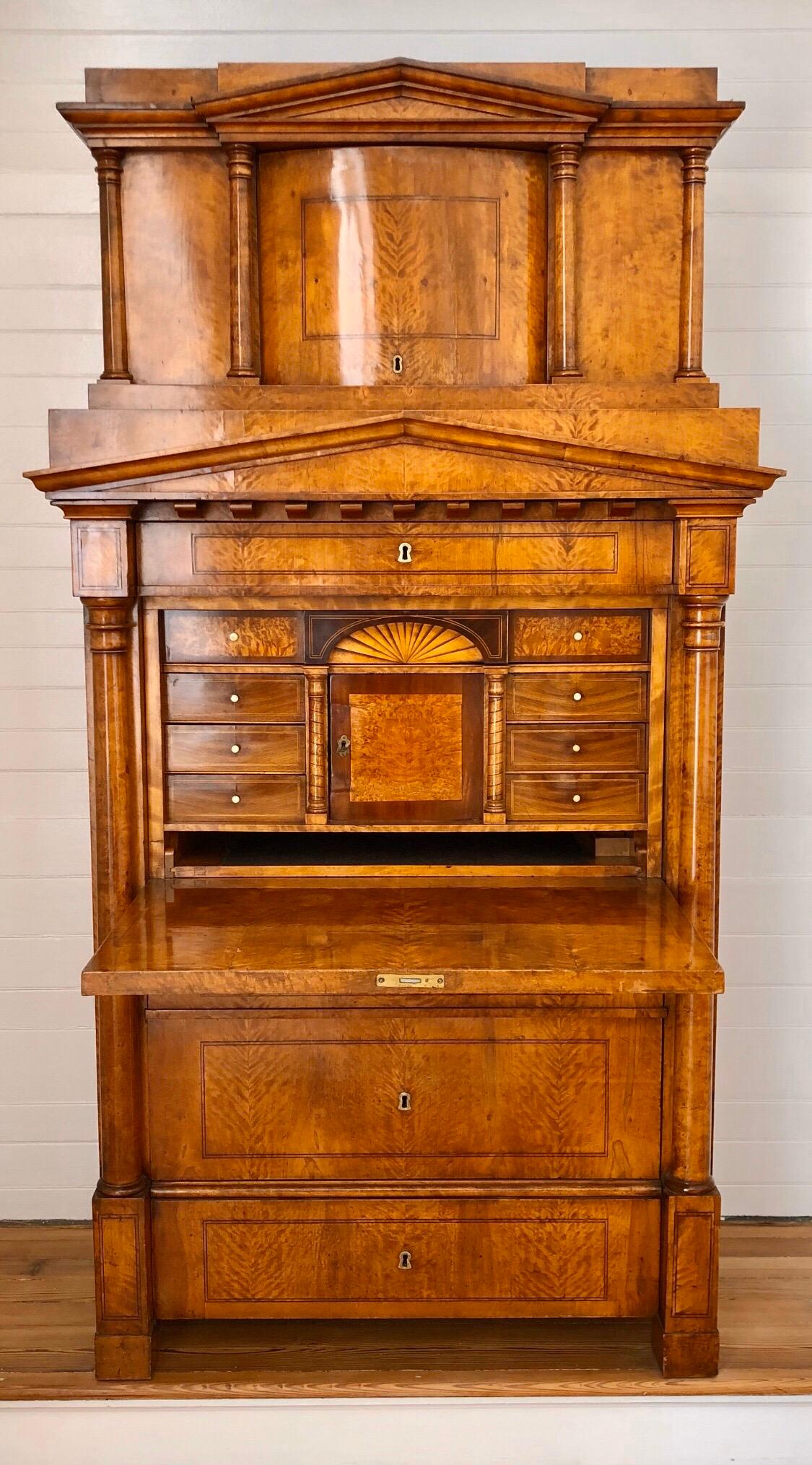 Questo monumentale secretaire Biedermeier di Berlino è uno degli esempi più belli con la sua architettura classica fatta di frontoni dorici, colonne e modanature dentali. La struttura principale del Segretariato presenta un maestoso mobile