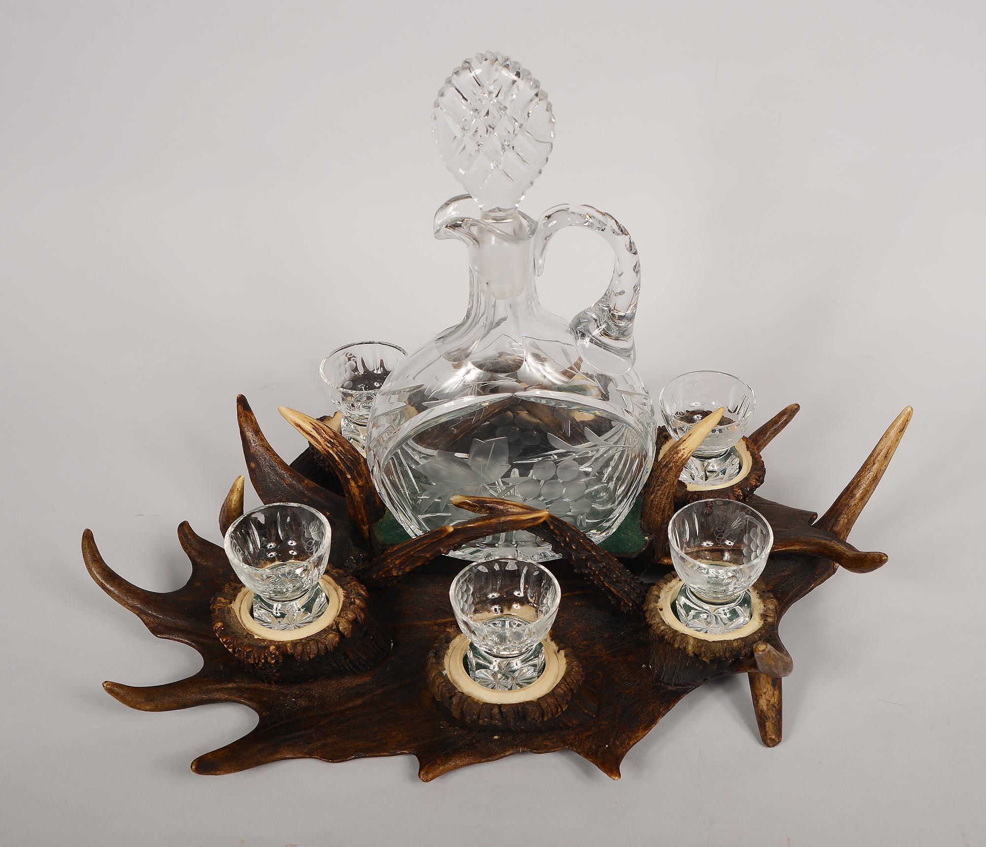 Unusual decanter set with a tray made of antlers. The set has a cut glass decanter with matching glasses. One glass is missing. Great display piece for a cabinet of curiosities, cabin or lodge.