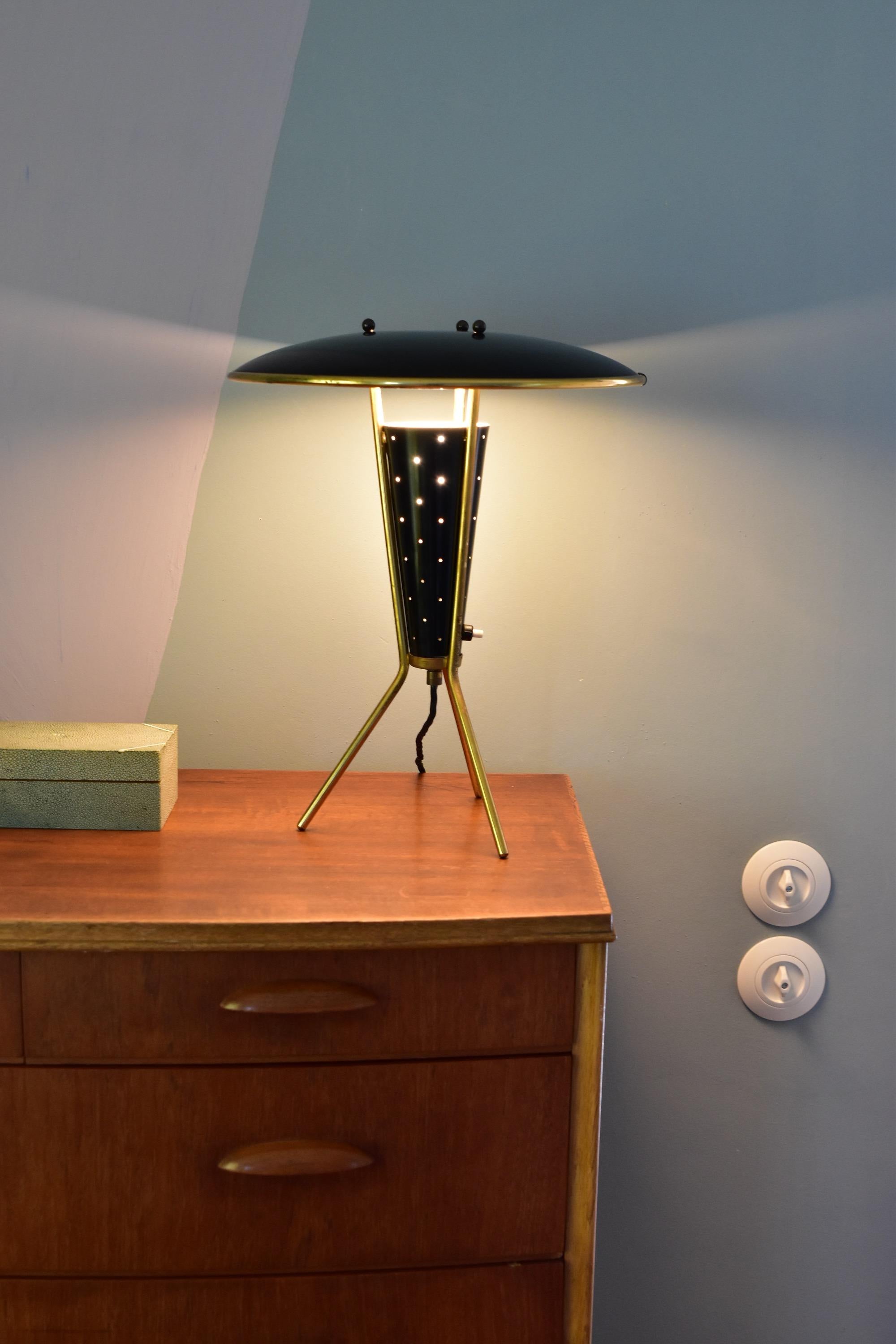 Midcentury tripod table in brass and black lacquered shade. The central black perforated cone houses the light source made soft indirect light. Very nice condition with beautiful patina and some loss of paint on the white reflector inside. With