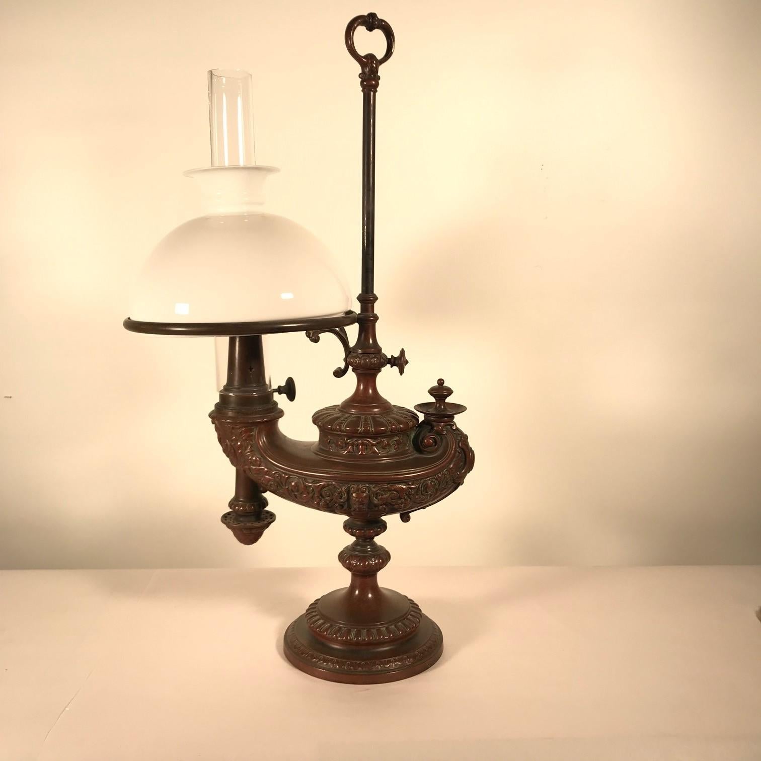 This Aladdin lamp is German, and dates from the late 19th century, The bronze is exquisitely cast in bas-relief with masks and scrolling acanthus. The base and knopped stem ,the sliding shade support, and reservoir are all crisply cast although