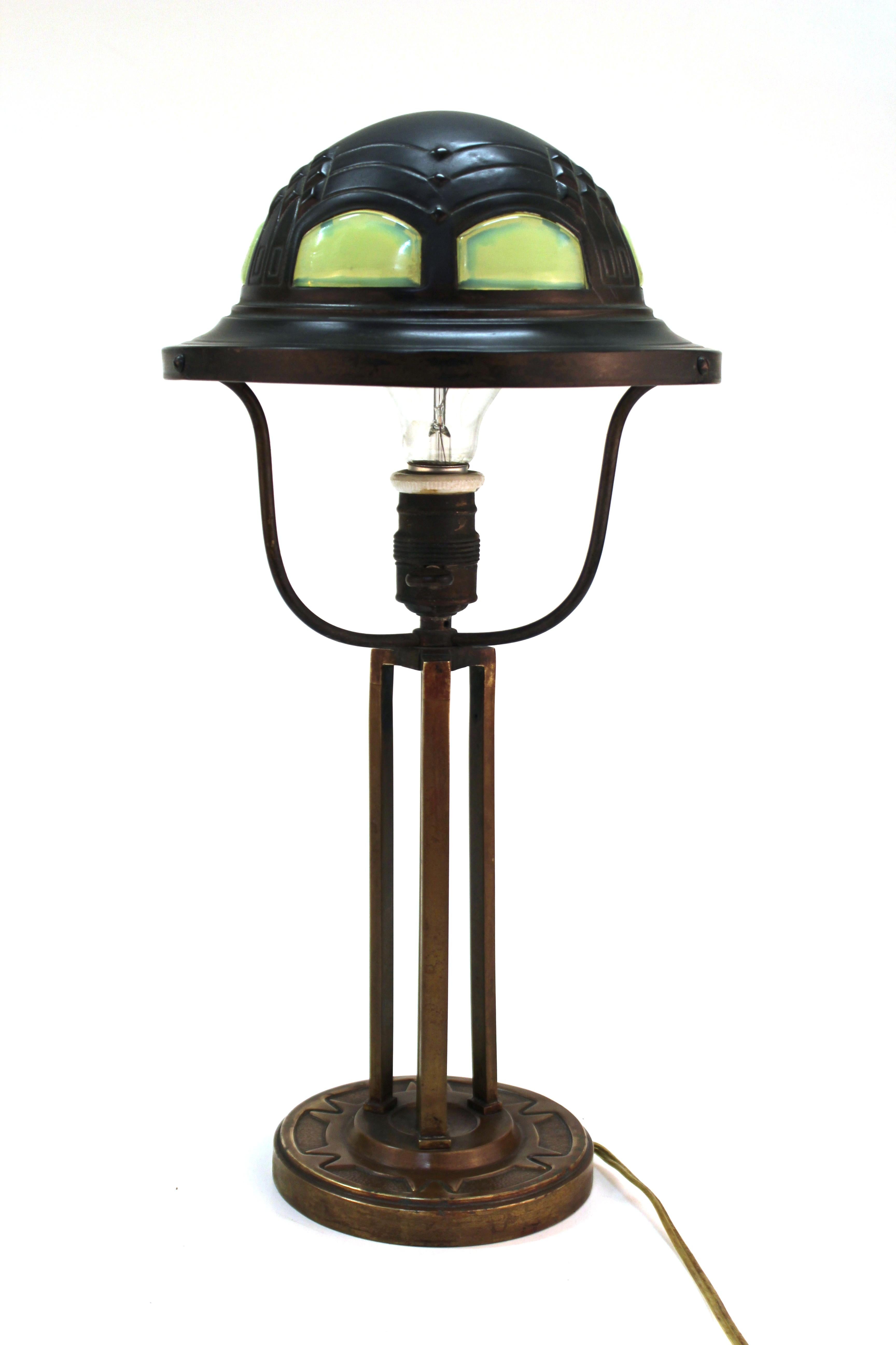 German Jugendstil table lamp attributed to architect and designer Peter Behrens from the Darmstadt Artists' Colony. The piece has a brass shade with inset opalescent art glass elements, atop a bronze base. Created in circa 1900. In great vintage