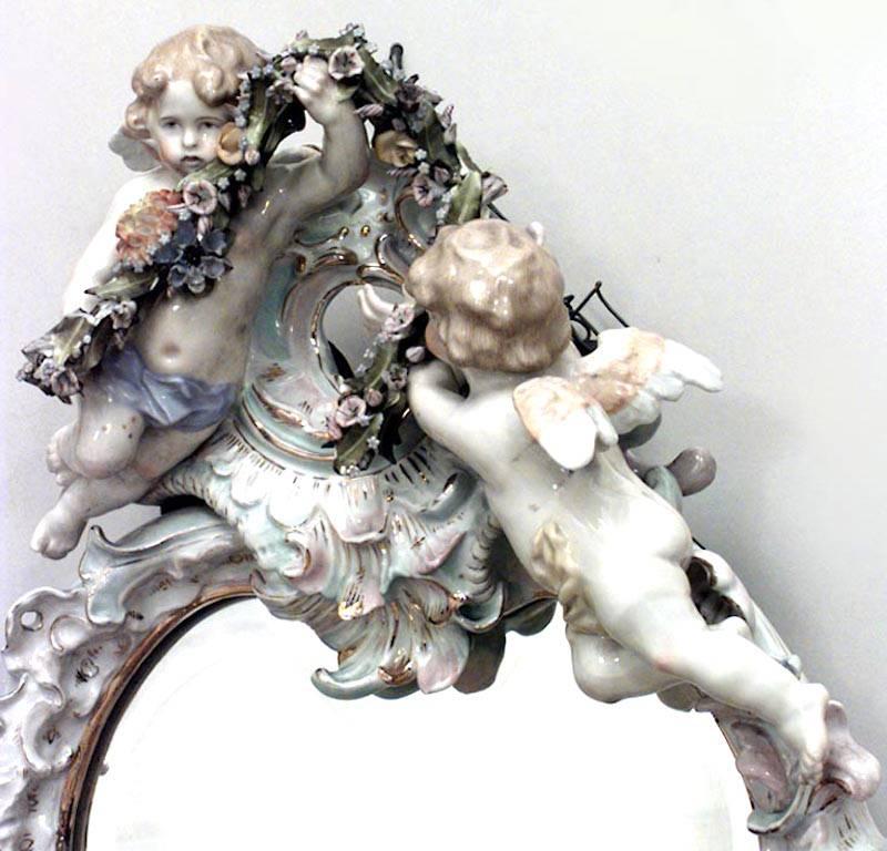 German Dresden (19th Century) porcelain wall mirror with beveled glass , two cherubs, and a garland at the top.
