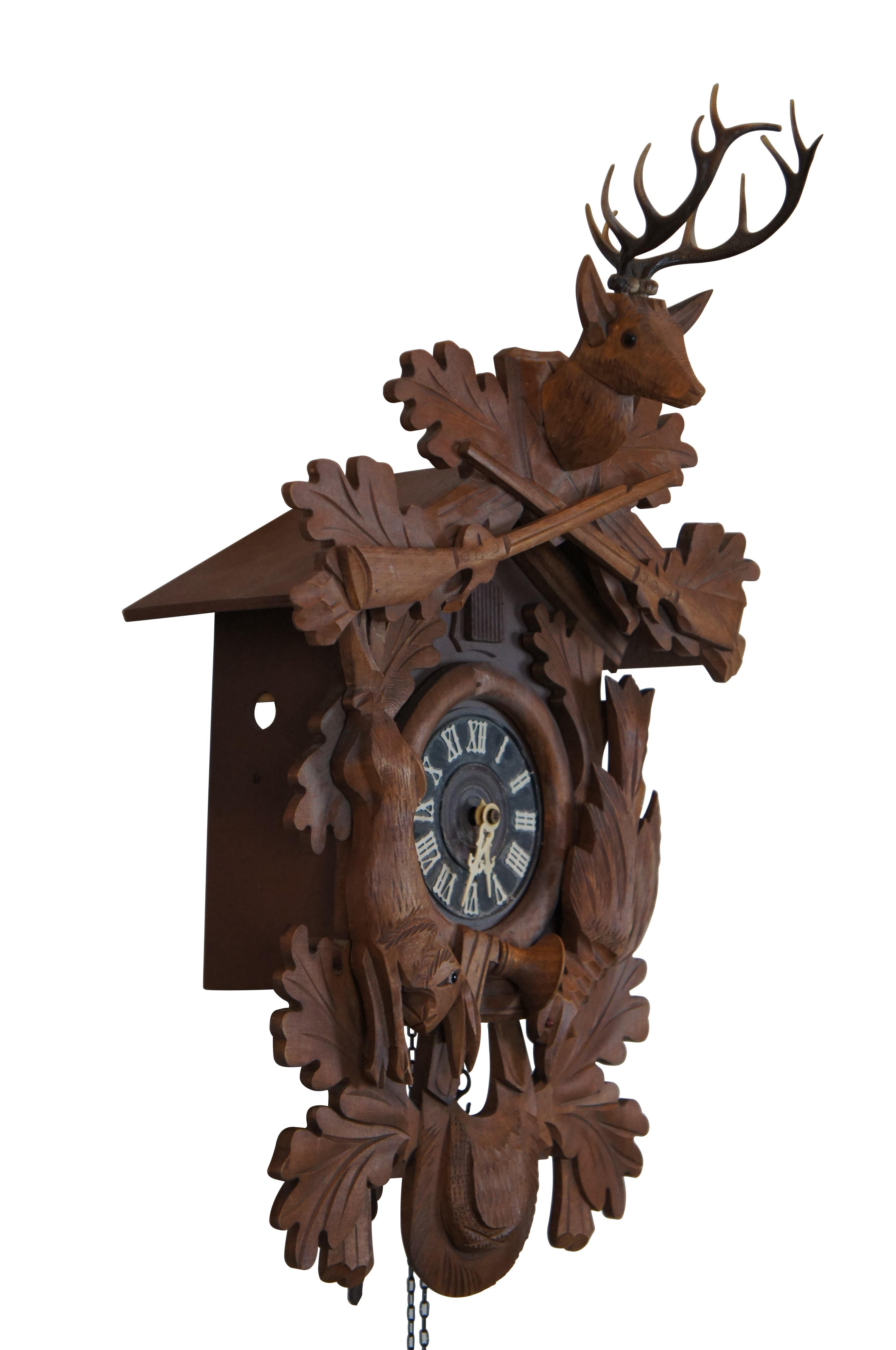 Vintage Mitte bis Ende des 20. Jahrhunderts Wandbehang, 8 Tage, läutende Kuckucksuhr von E. Schmeckenbecher. Aus Holz geschnitztes Schwarzwaldjäger-Motiv mit Eichenlaub, Gewehren, Jagdtasche und Wild, gekrönt von einem Hirschkopf mit Glasaugen und