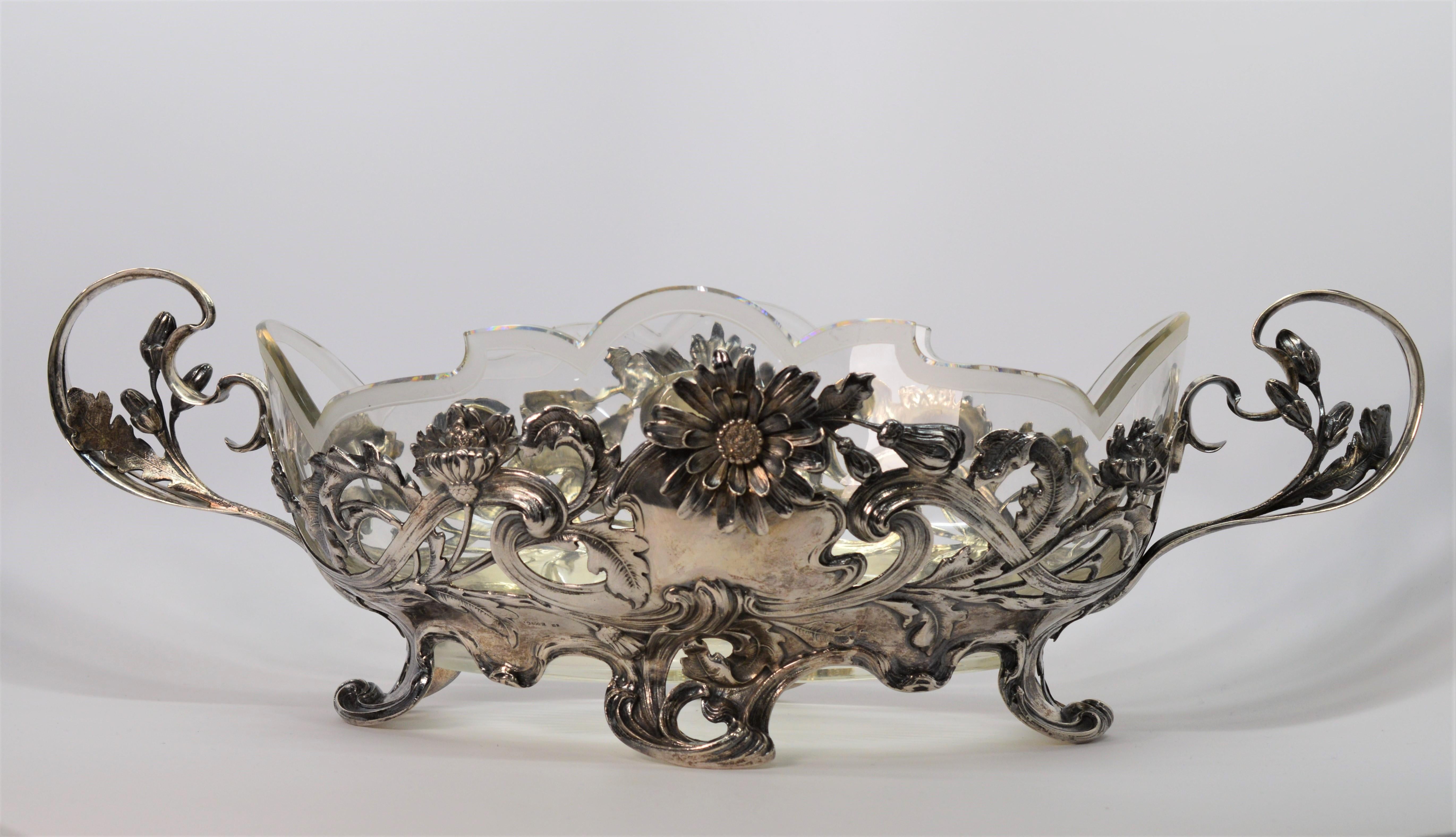 In excellent condition, this exquisite bowl is a work of art with it's intricate floral vine patterned design done is .800 German Silver. 
Intact is a frosted leaded glass insert that allows for versatility of use. Measures 18L x 7-1/2W  x 6H. Known