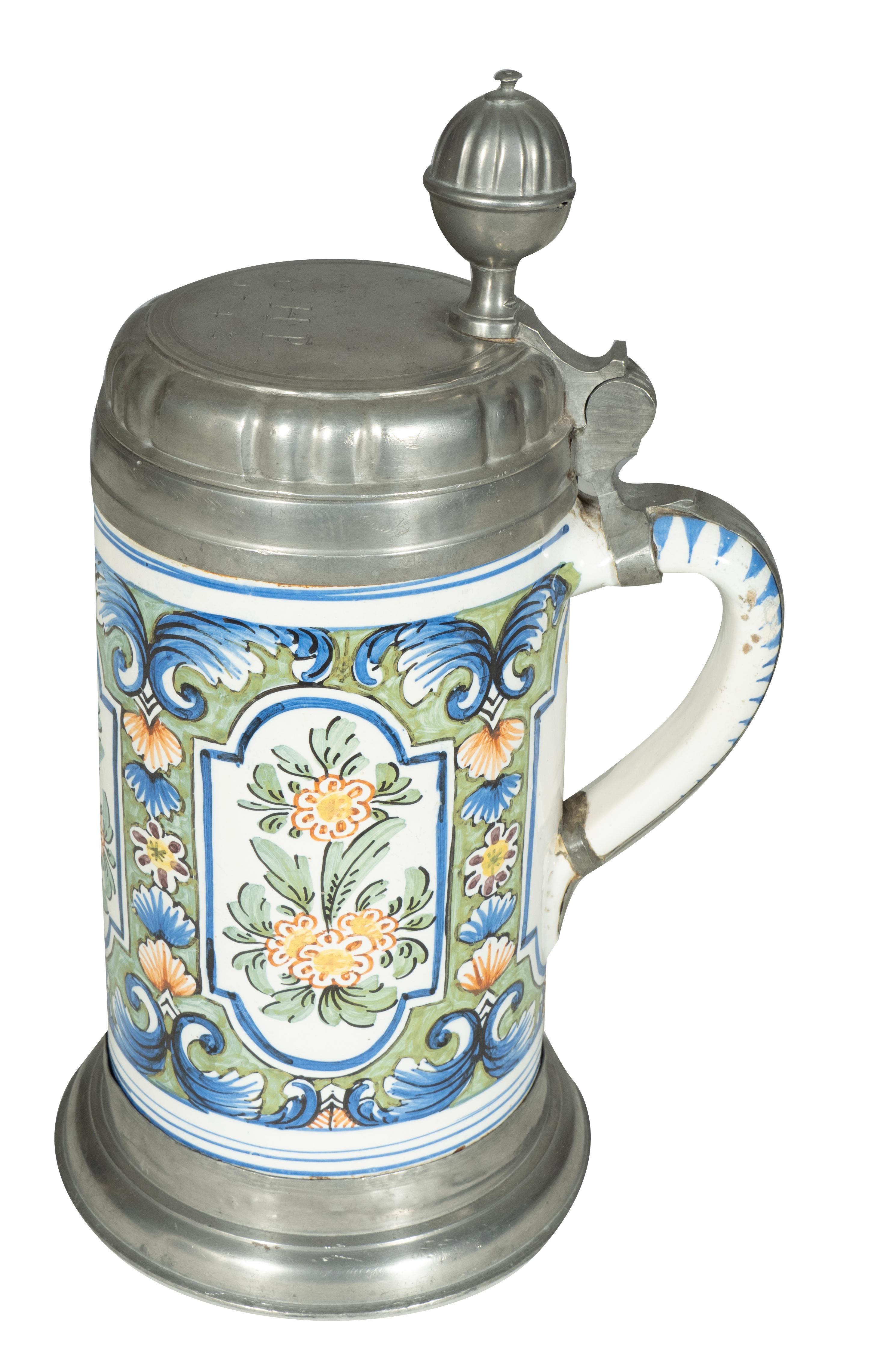 Cilíndrico con tapa de peltre. Decoración floral y asa de lazo.