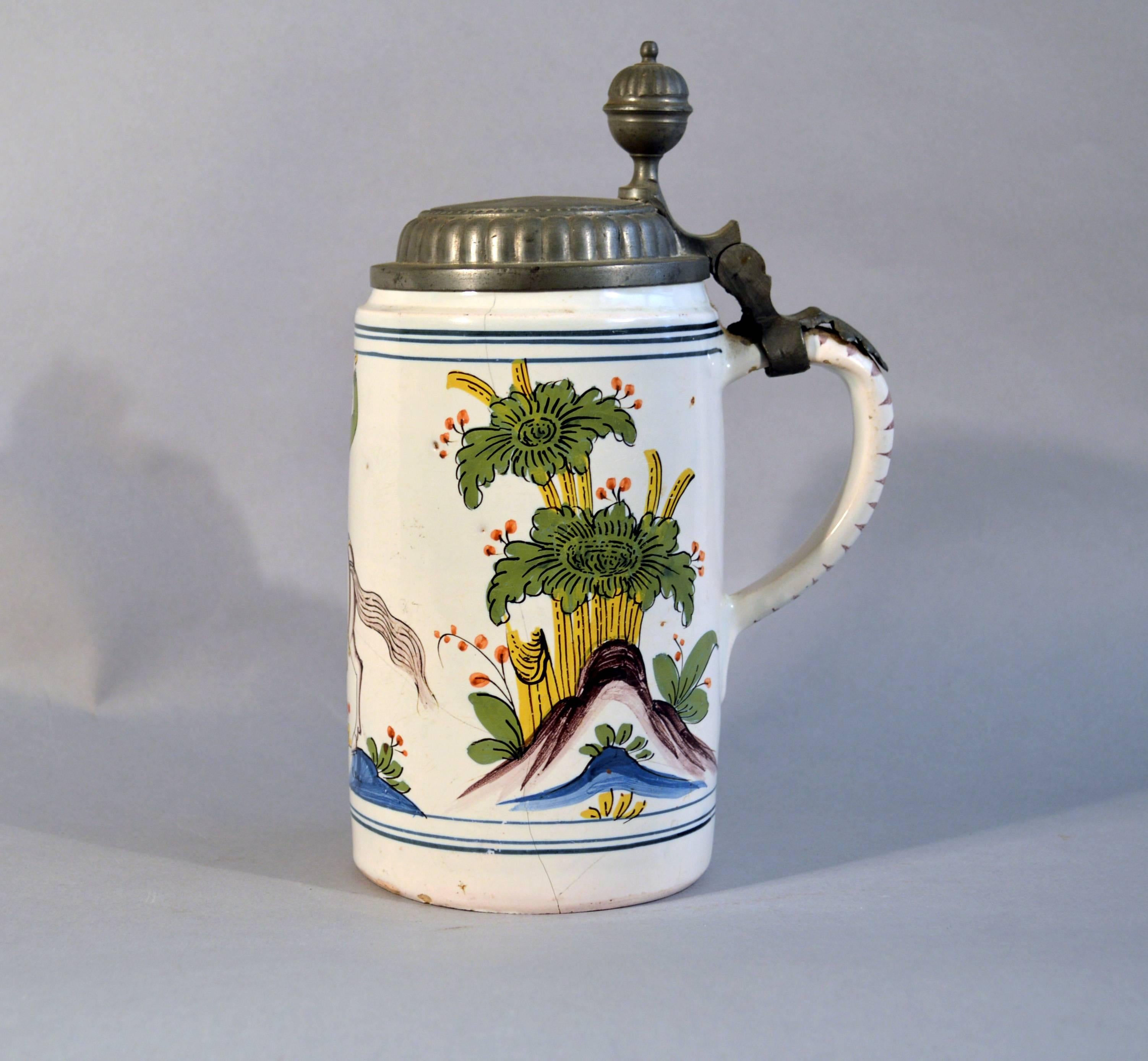 German Faience Pewter-mounted Tankard, 
Probably Thuringia,
circa 1750

A tin-glazed earthenware tankard with polychrome decoration and pewter cover. The tankard depicts a Turkish horseman with a saber held high over his head with trees and
