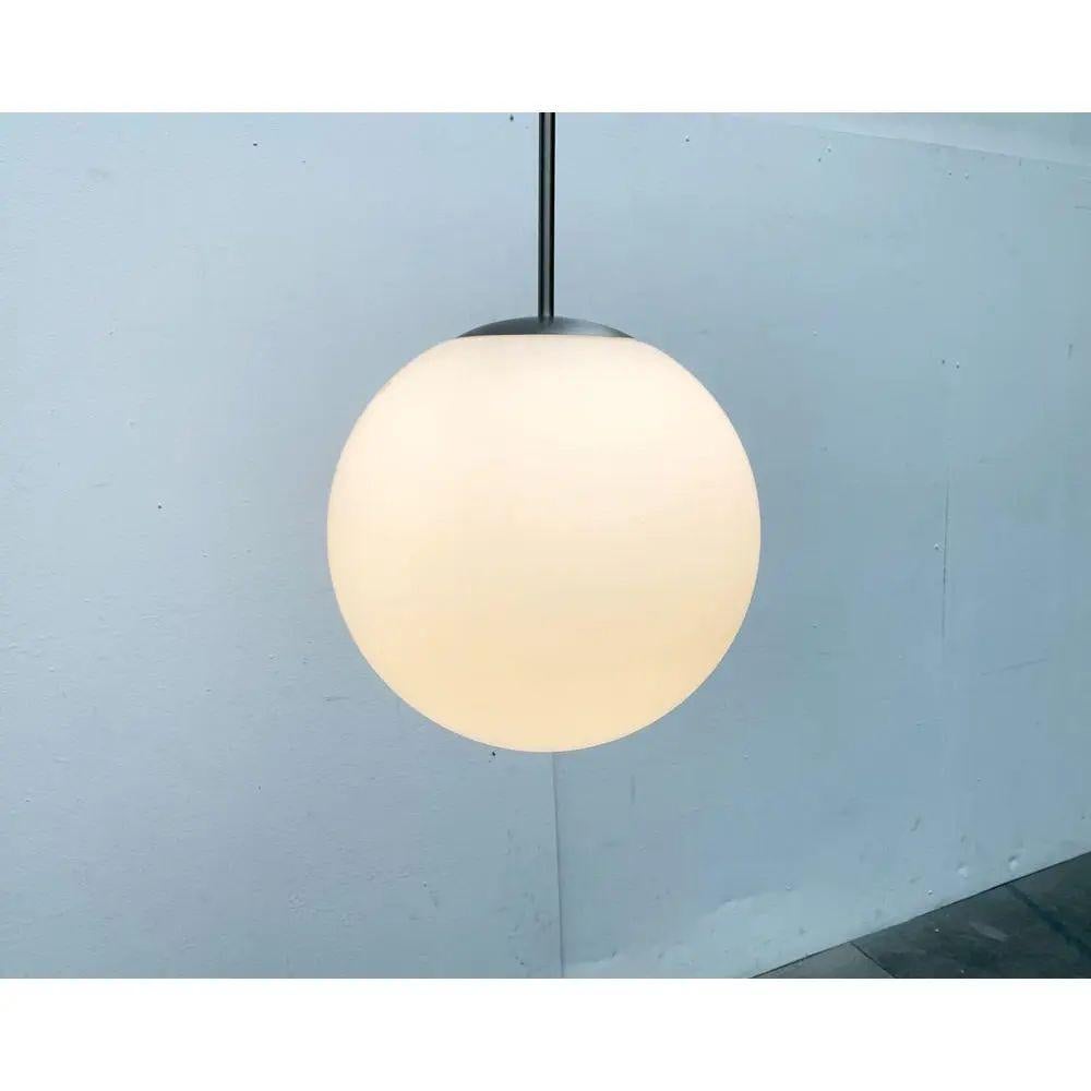 Grand pendentif boule en verre de Putzler.

Lampe suspendue boule classique. La taille imposante de la sphère en verre opale de 35 cm est frappante. La fixation s'intègre parfaitement à la forme de la boule du diffuseur. Le baldaquin assorti est
