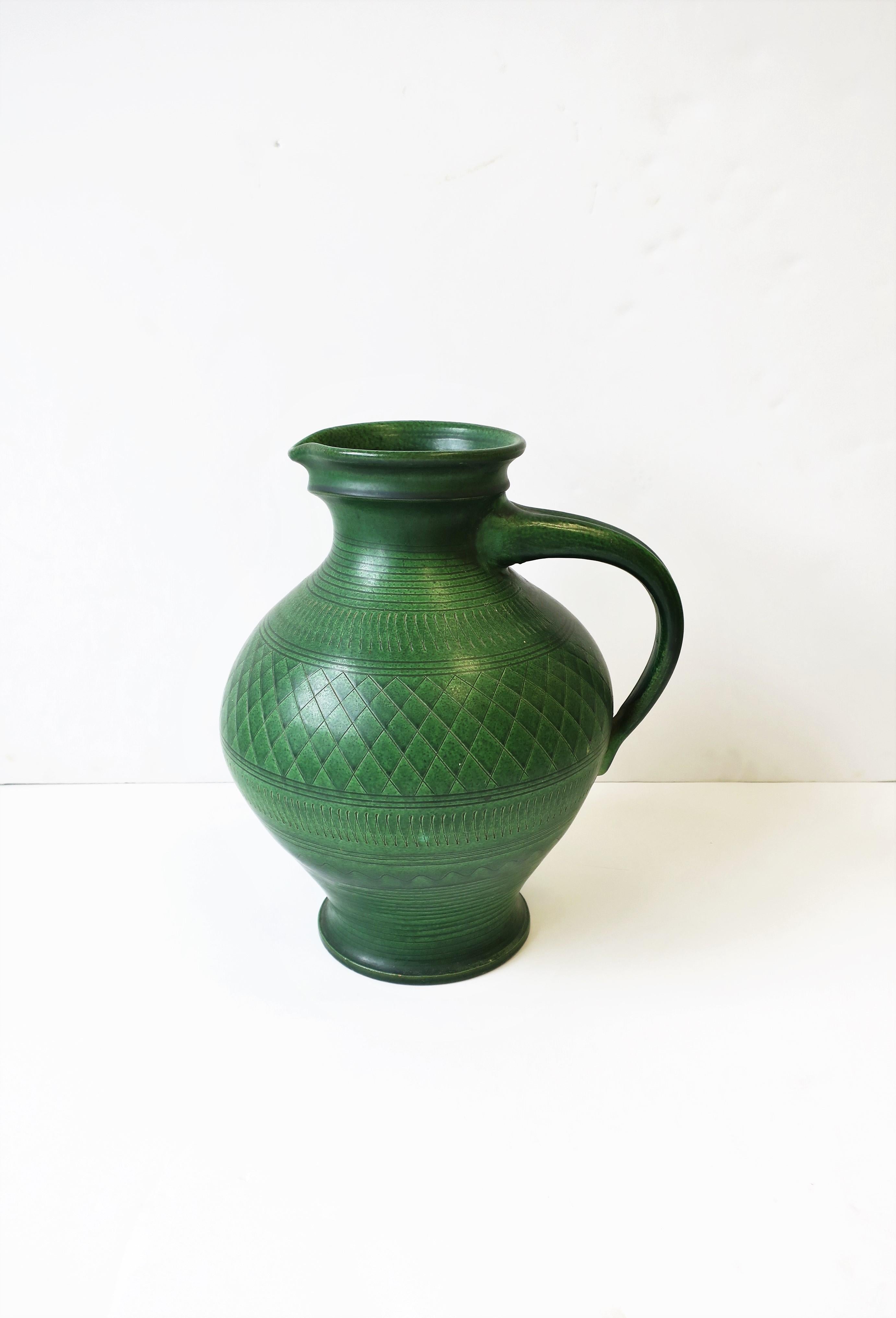 A relatively large German handmade (thrown) green pottery pitcher or vessel/vase, by Wilhelm Kagel, circa 20th century, West Germany. Piece is in the Art Nouveau style. Beautiful handcut decorative pattern around. Maker's mark: WK (Wilhelm Kagel)