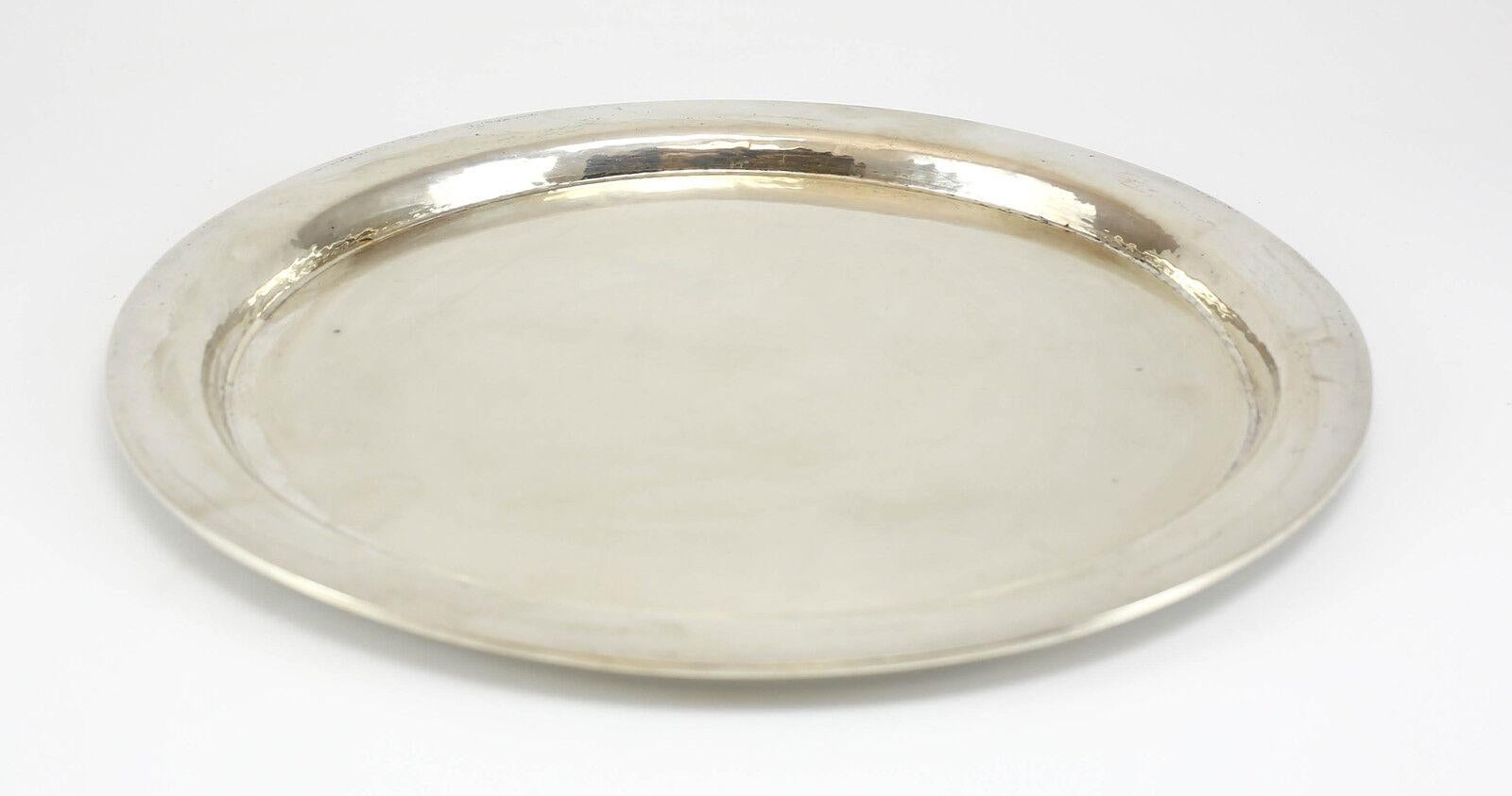 German Handarbeit .900 silver circular hand hammered tray, Makers Mark.

Makers Mark & Marked .900 on Reverse.

Additional Information:
Maker: Handarbeit 
Weight: 26 ozt 
Type: Platters & Trays
Composition: Coin Silver
Dimension: 13