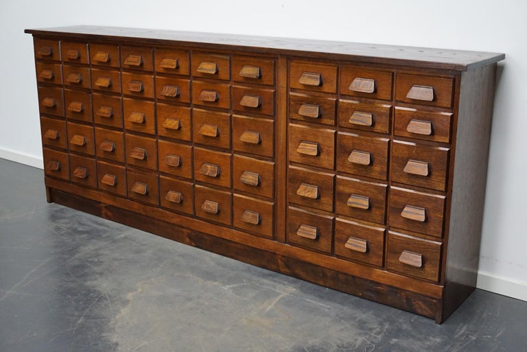 This apothecary cabinet was made circa 1930s in Germany and was later used in a hardware store in Belgium until recently. It features many drawers in two different sizes with oak handles. The interior dimensions of the drawers are: DWH 31 x 16 x 8 /