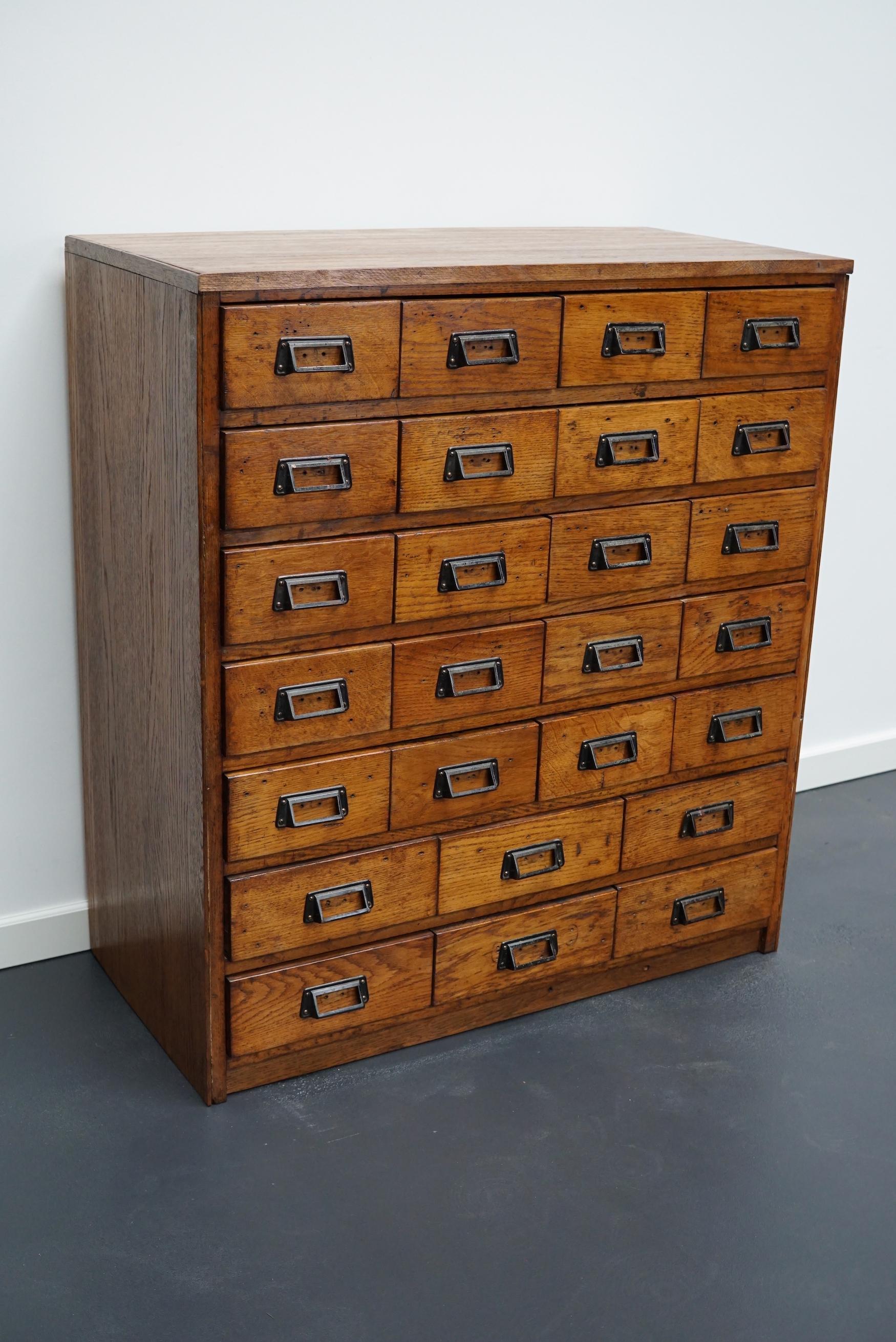 This apothecary cabinet was made circa 1950s in Germany. It features 26 drawers with black metal handles. The interior dimensions of the drawers are: D x W x H 38.5 x 17.5 x 9 cm and 38.5 x 24 x 9 cm.